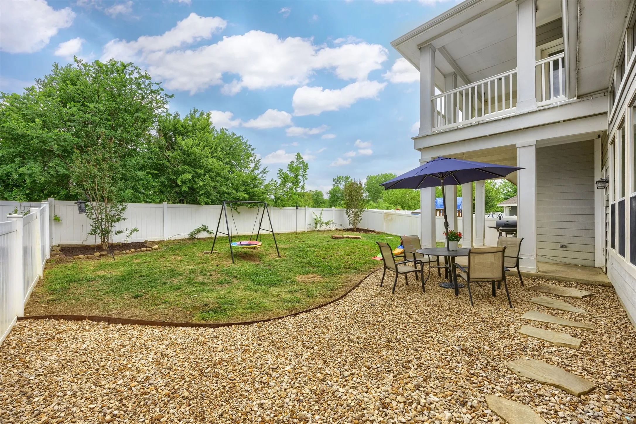 The property features a spacious backyard with a gravel patio area, stone stepping pads, and a manicured lawn