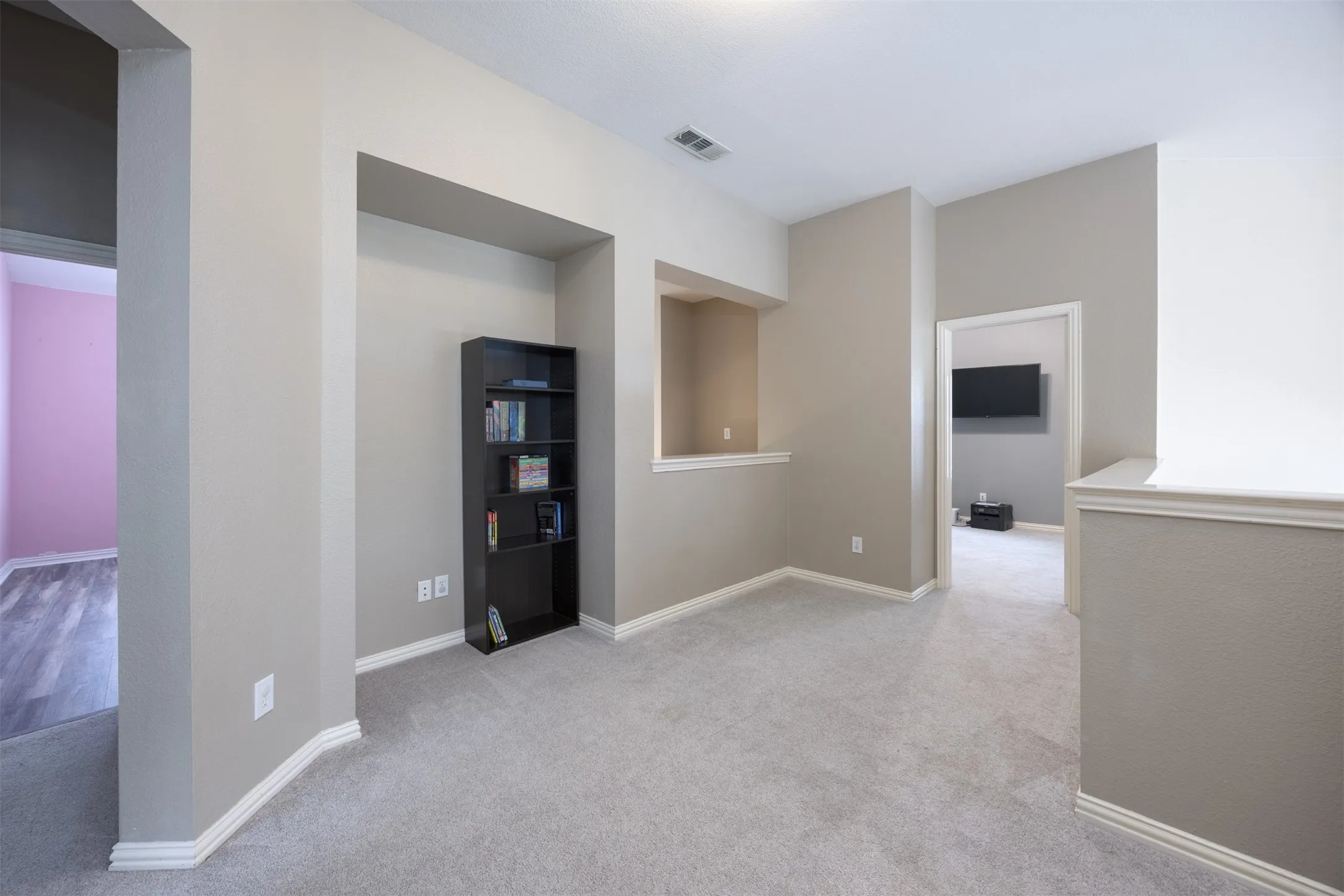 Spacious room featuring light gray carpeting, neutral-toned walls, and white baseboards