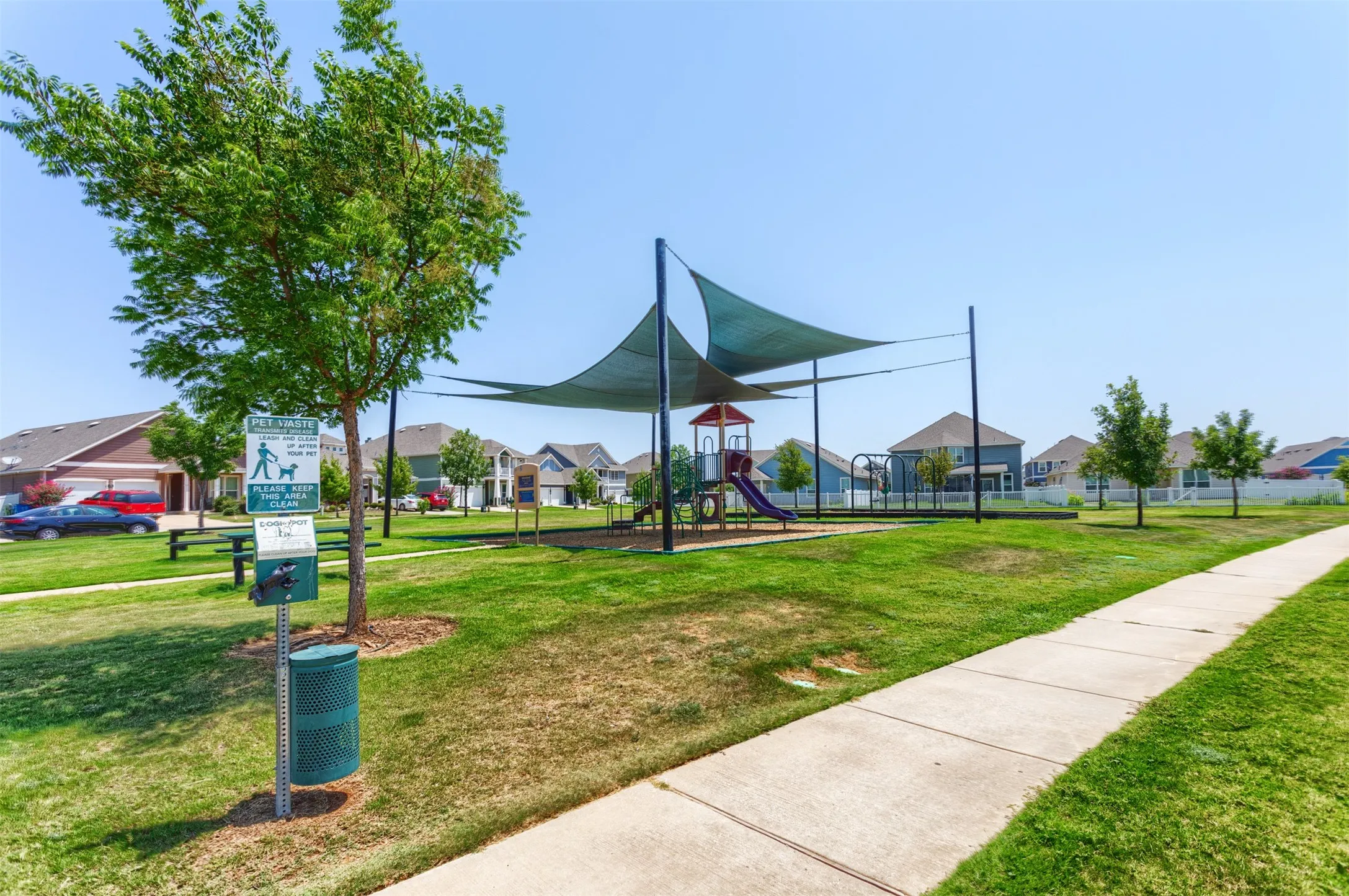 Community green space featuring a playground with shade sails and a paved pathway