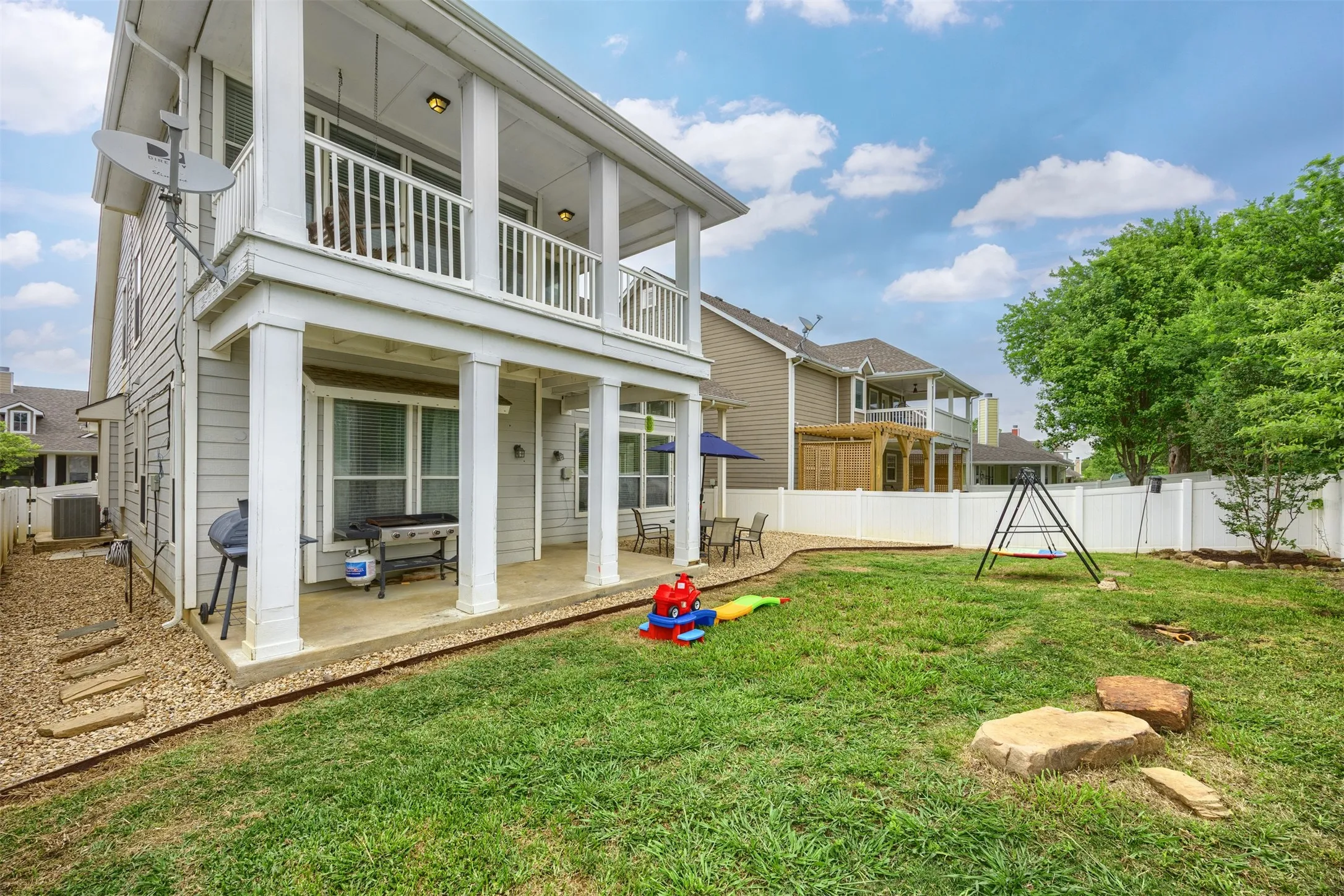 The property features a spacious backyard with a well-maintained lawn and a white privacy fence