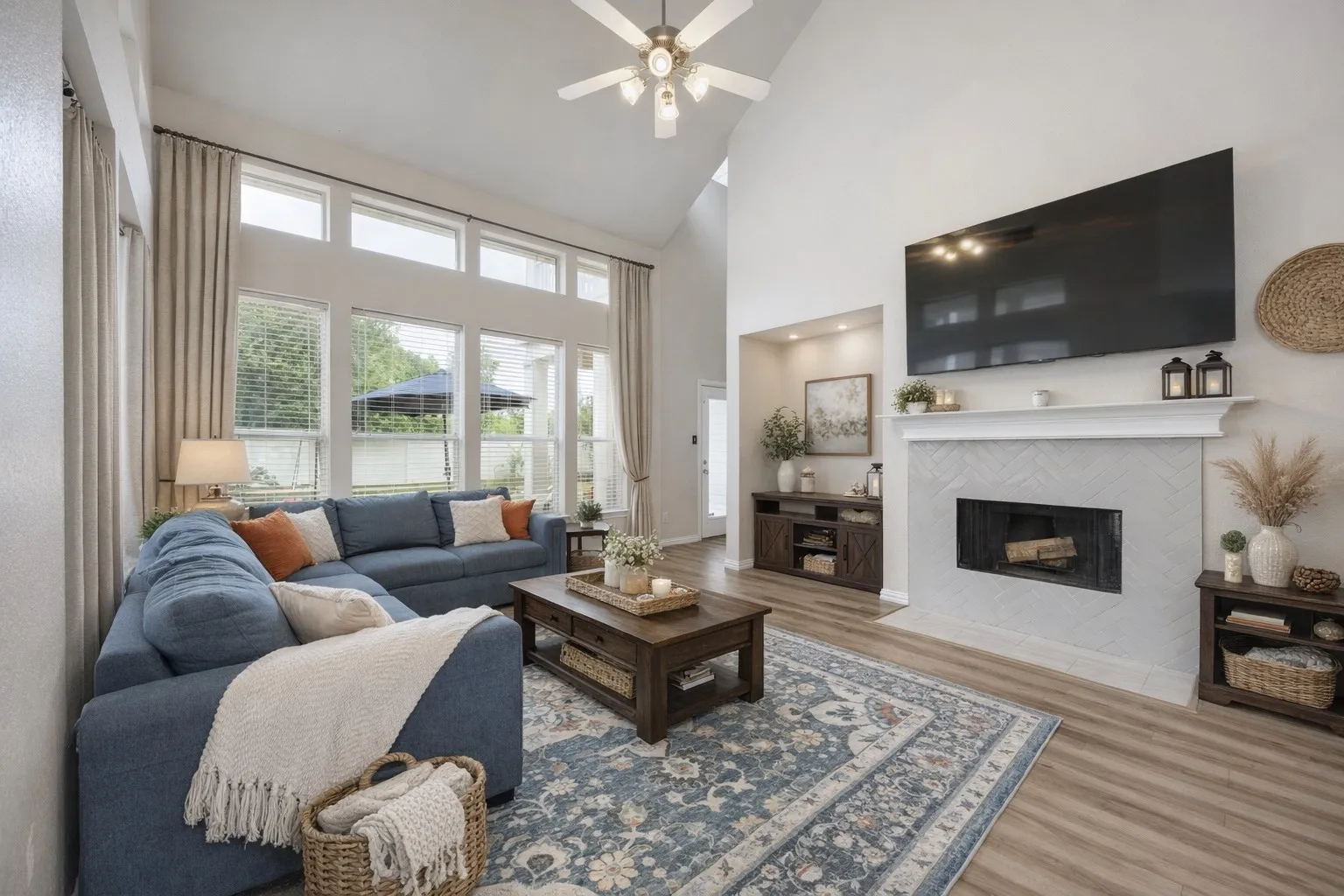 Spacious living area featuring high vaulted ceilings, large windows providing ample natural light, and light-colored flooring