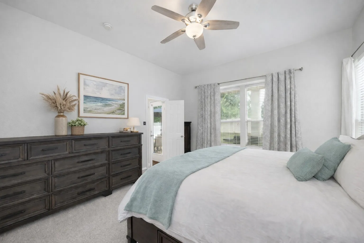 This bedroom features a ceiling fan with integrated lighting, window treatments, and a window providing natural light