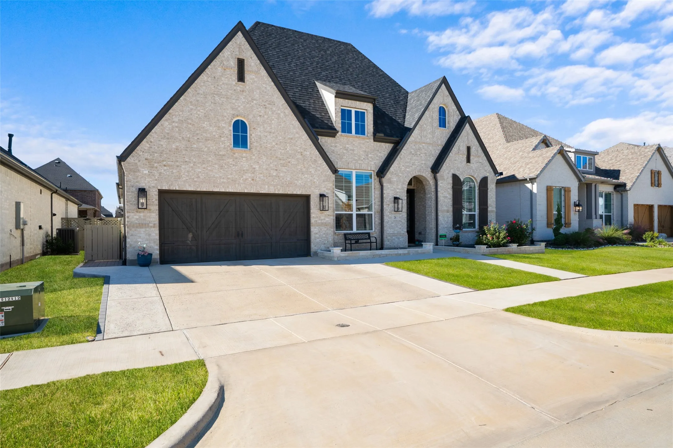This property features a light-colored brick exterior with dark trim and a dark roof, complemented by a concrete driveway and walkway