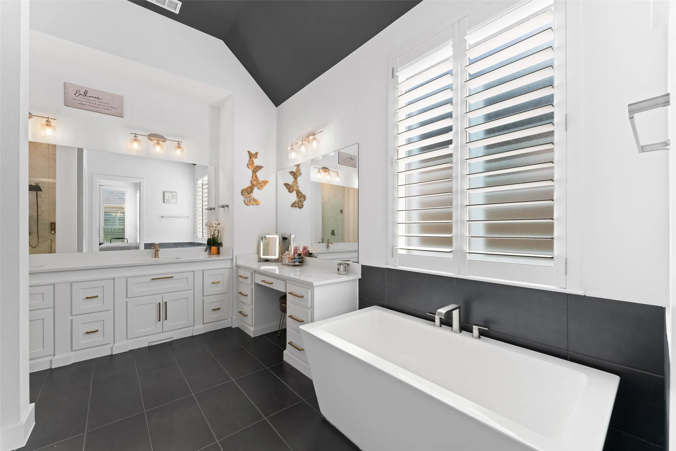 Spacious bathroom featuring a freestanding soaking tub, a large vanity with dual sinks, and a makeup vanity