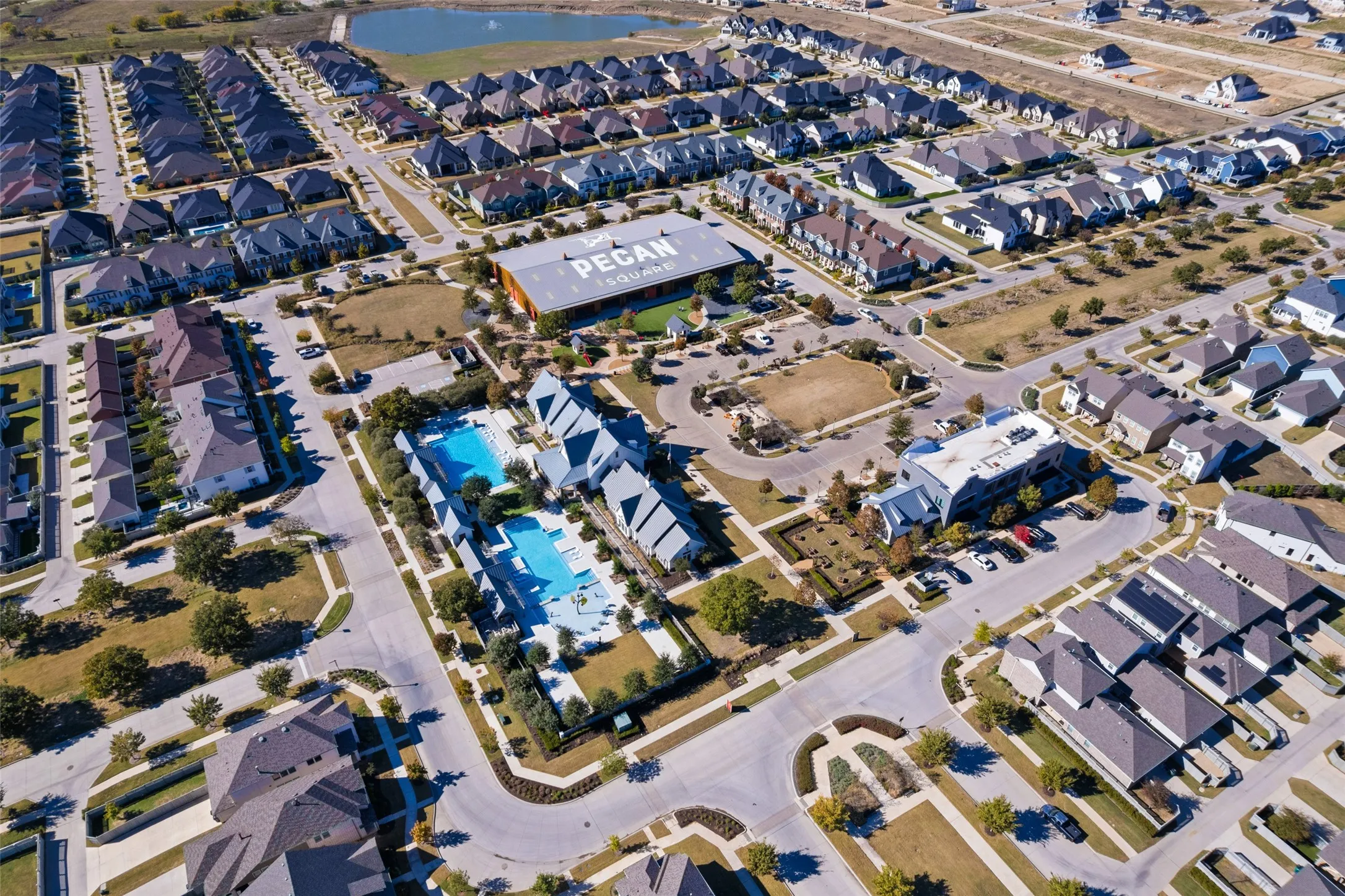 Aerial view of the community, featuring numerous residential properties with dark-colored roofs
