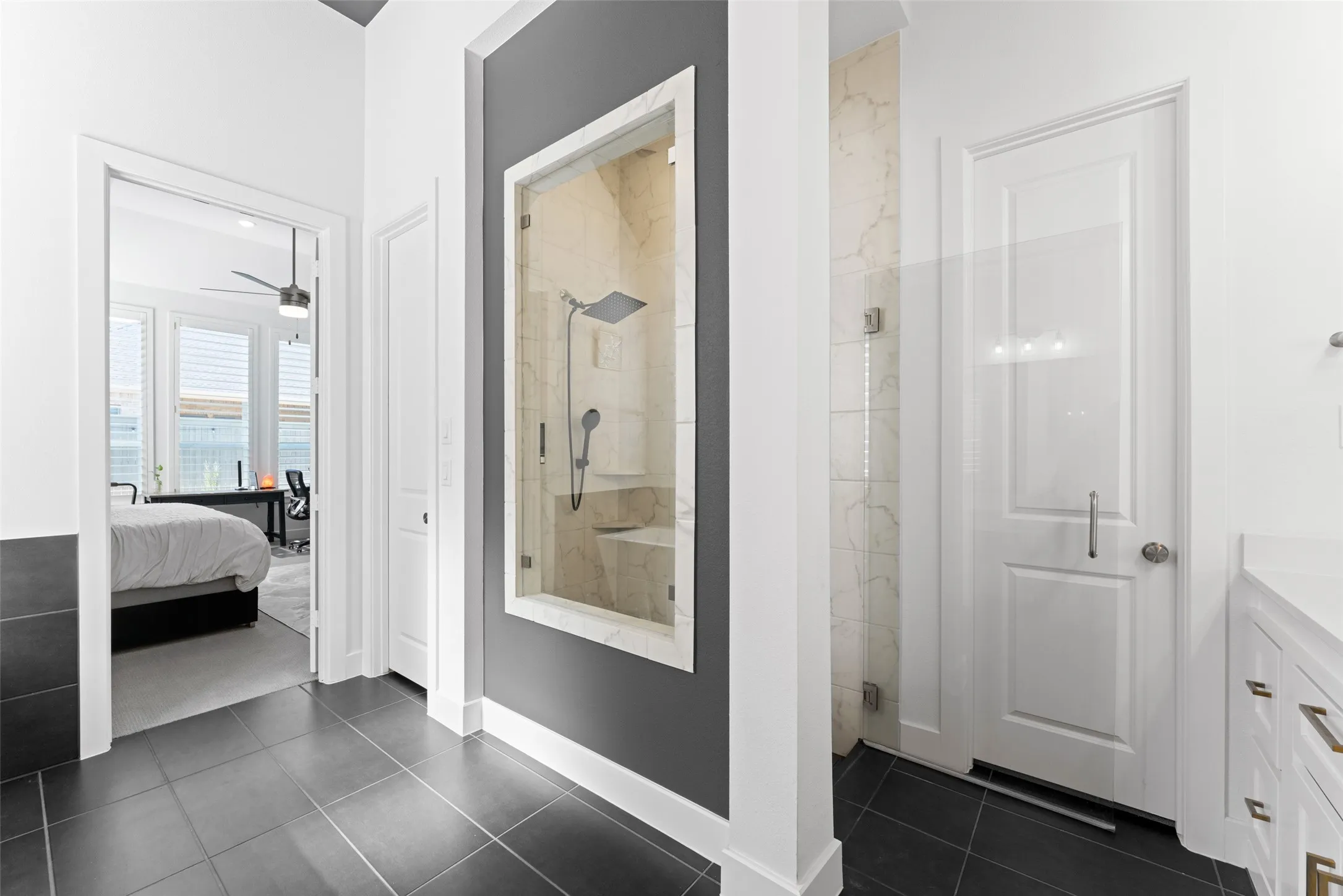The property features dark tile flooring, a glass-enclosed shower with a built-in bench, and white walls