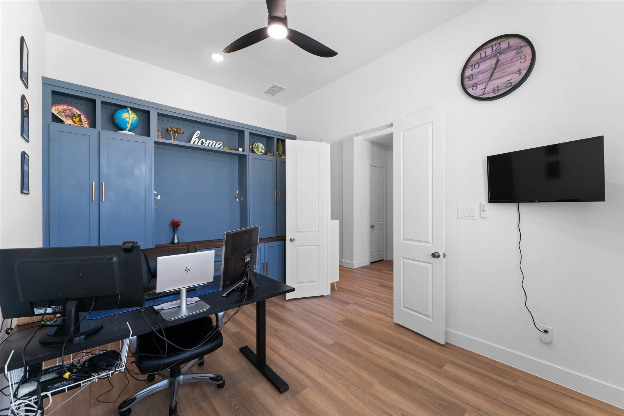 This room features wood-look flooring, a ceiling fan, and a built-in blue storage unit with shelving