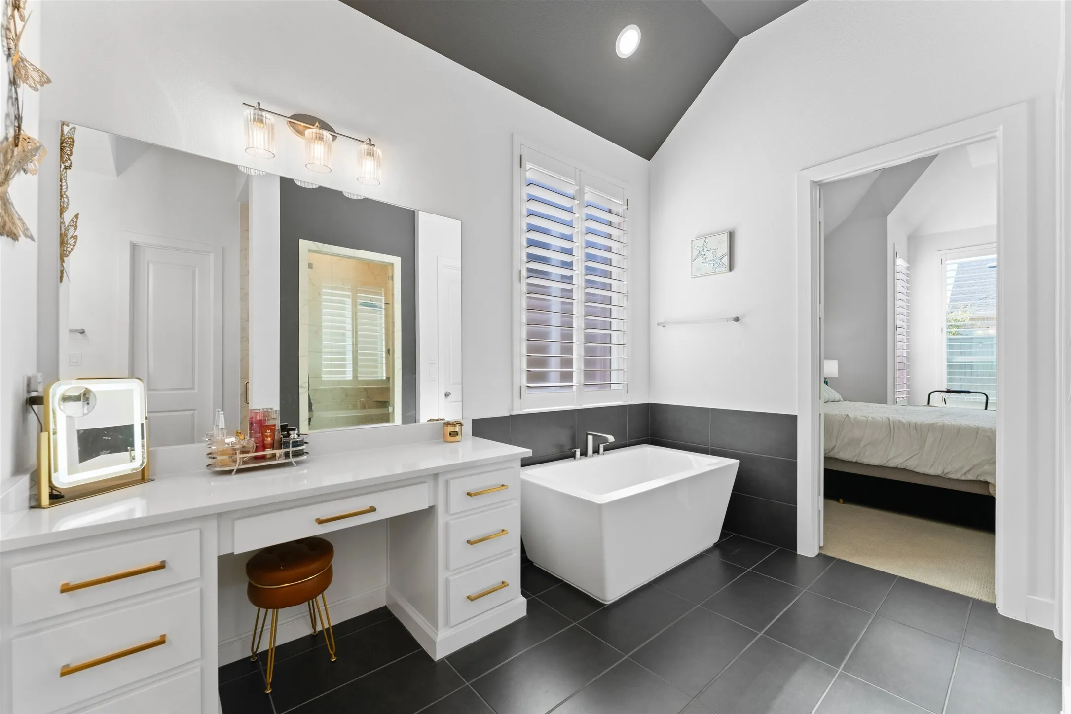 This bathroom features a contemporary freestanding bathtub, a vanity with ample storage and a large mirror, and tiled flooring