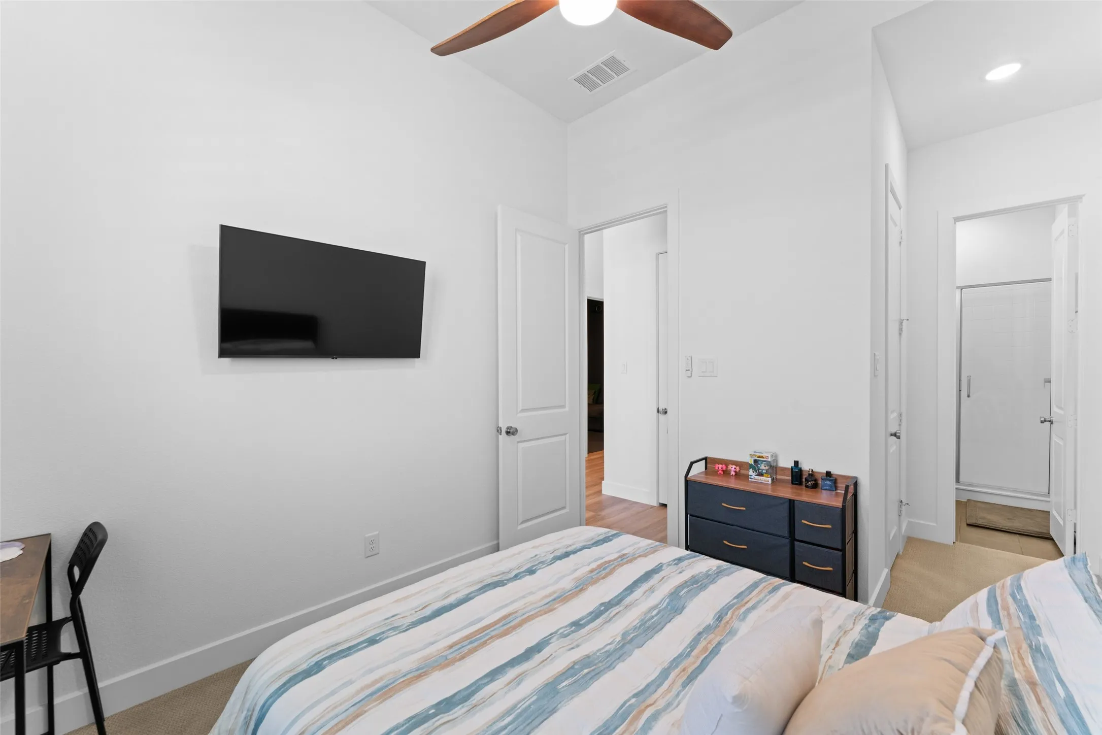The room features light-colored walls and flooring, with a ceiling fan providing air circulation