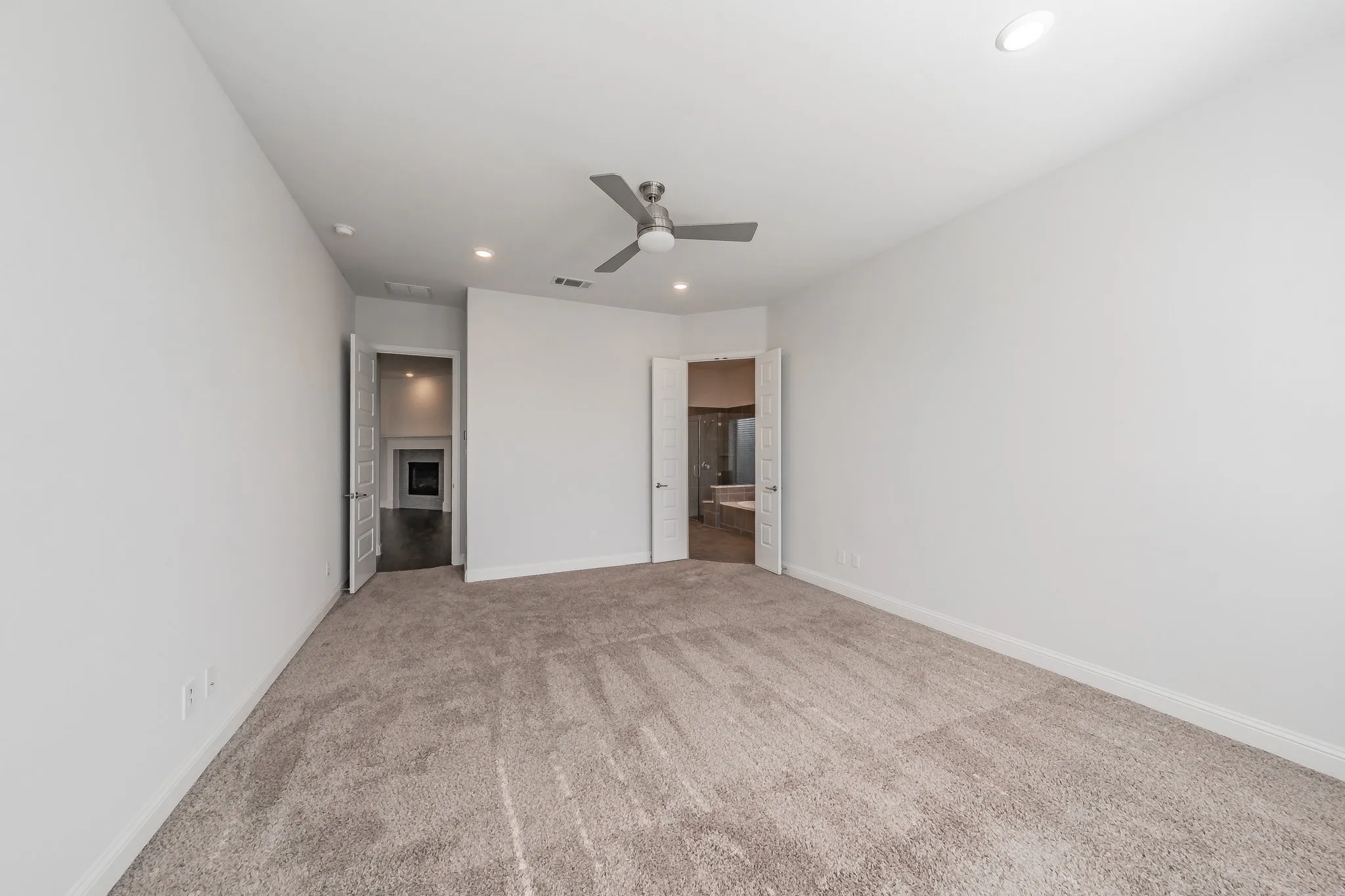 Unfurnished bedroom with ensuite bathroom, recessed lighting, light colored carpet, and a ceiling fan
