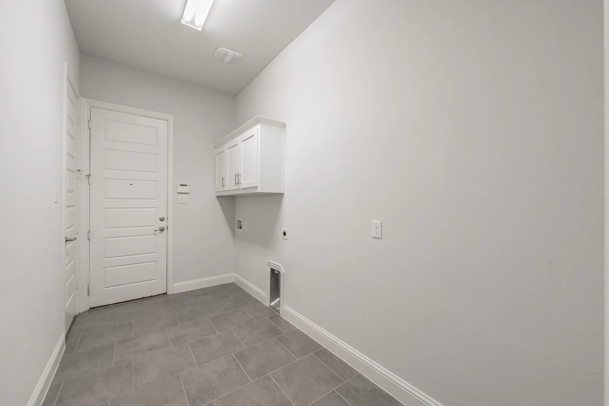 Laundry room with cabinet space, electric dryer hookup, light tile patterned floors, and washer hookup