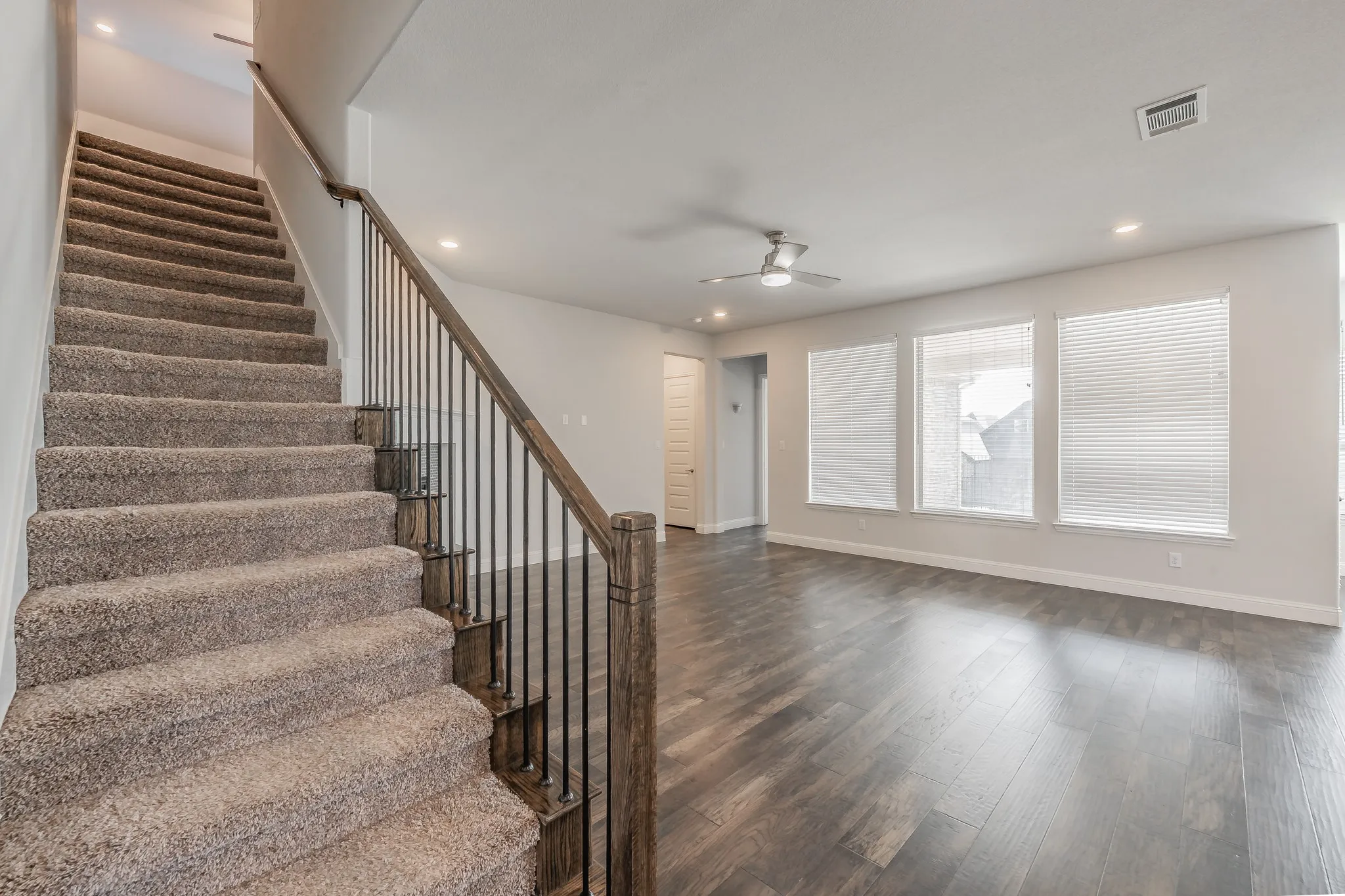 Staircase featuring wood finished floors, a ceiling fan, and recessed lighting