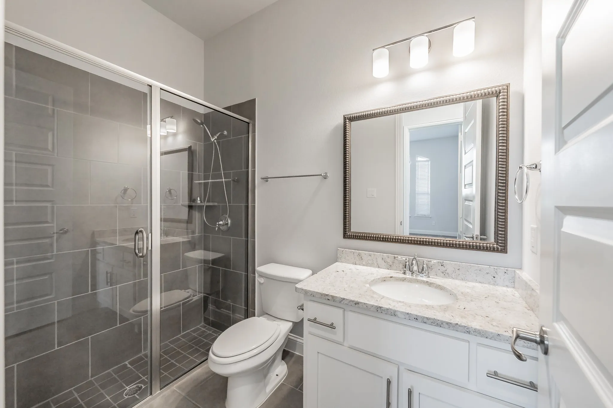 Full bath featuring vanity, a shower stall, and dark tile patterned floors