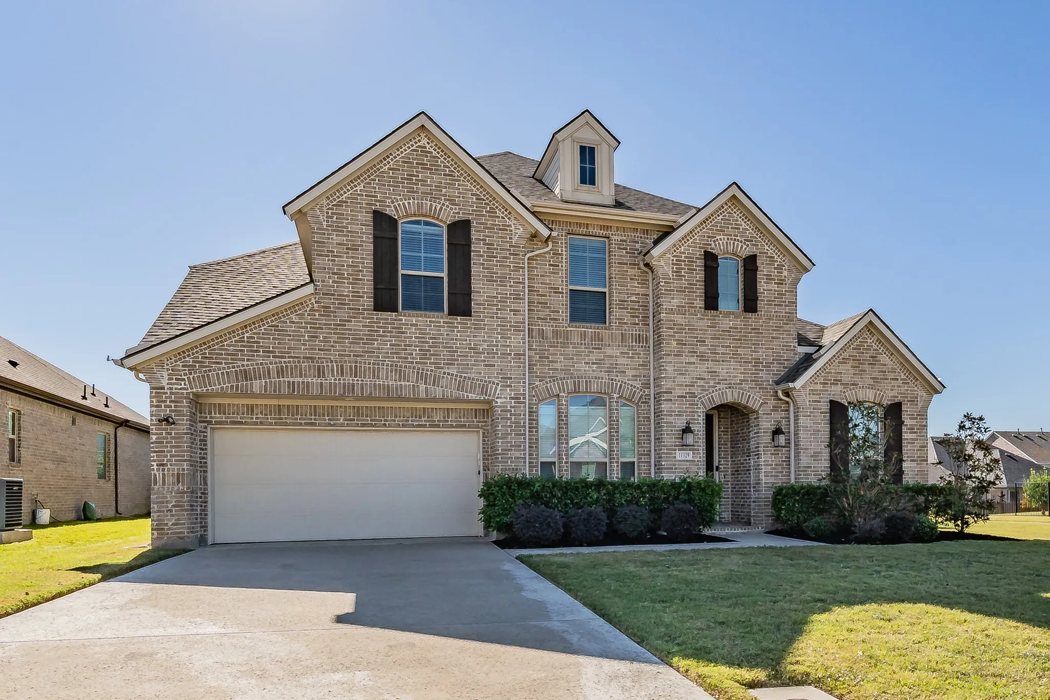 View of front of home featuring brick siding, a front yard, concrete driveway, and a shingled roof