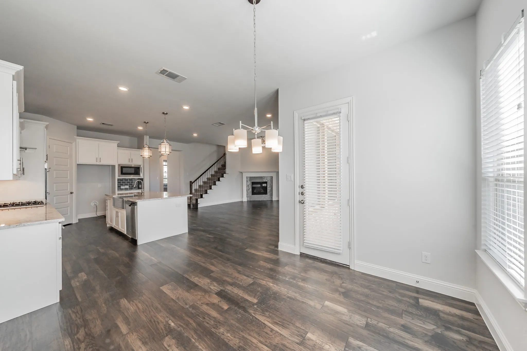 Kitchen featuring a center island, open floor plan, decorative light fixtures, dark wood-type flooring, and white cabinetry