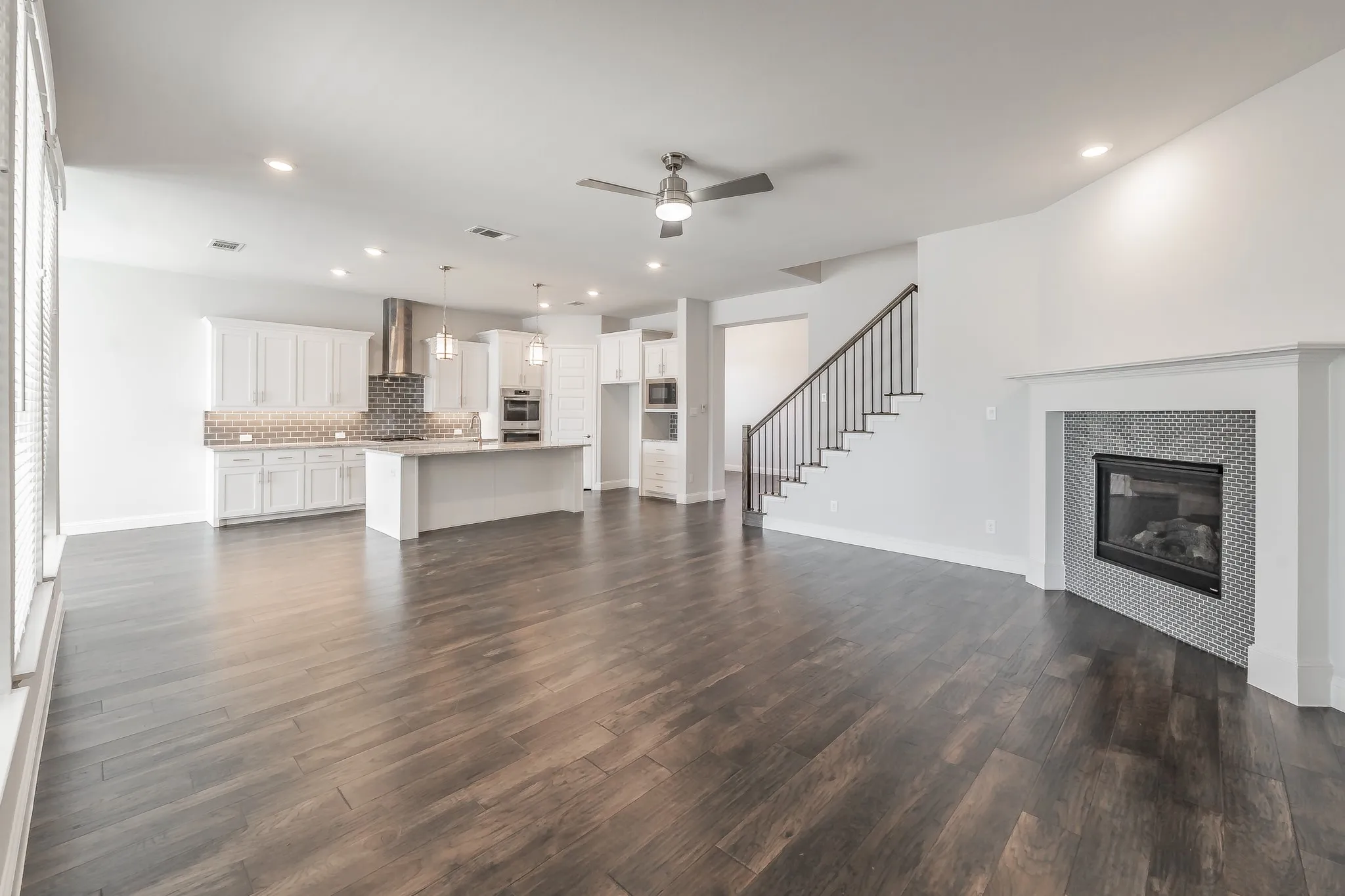 Unfurnished living room with a ceiling fan, recessed lighting, dark wood-style floors, stairway, and a tile fireplace