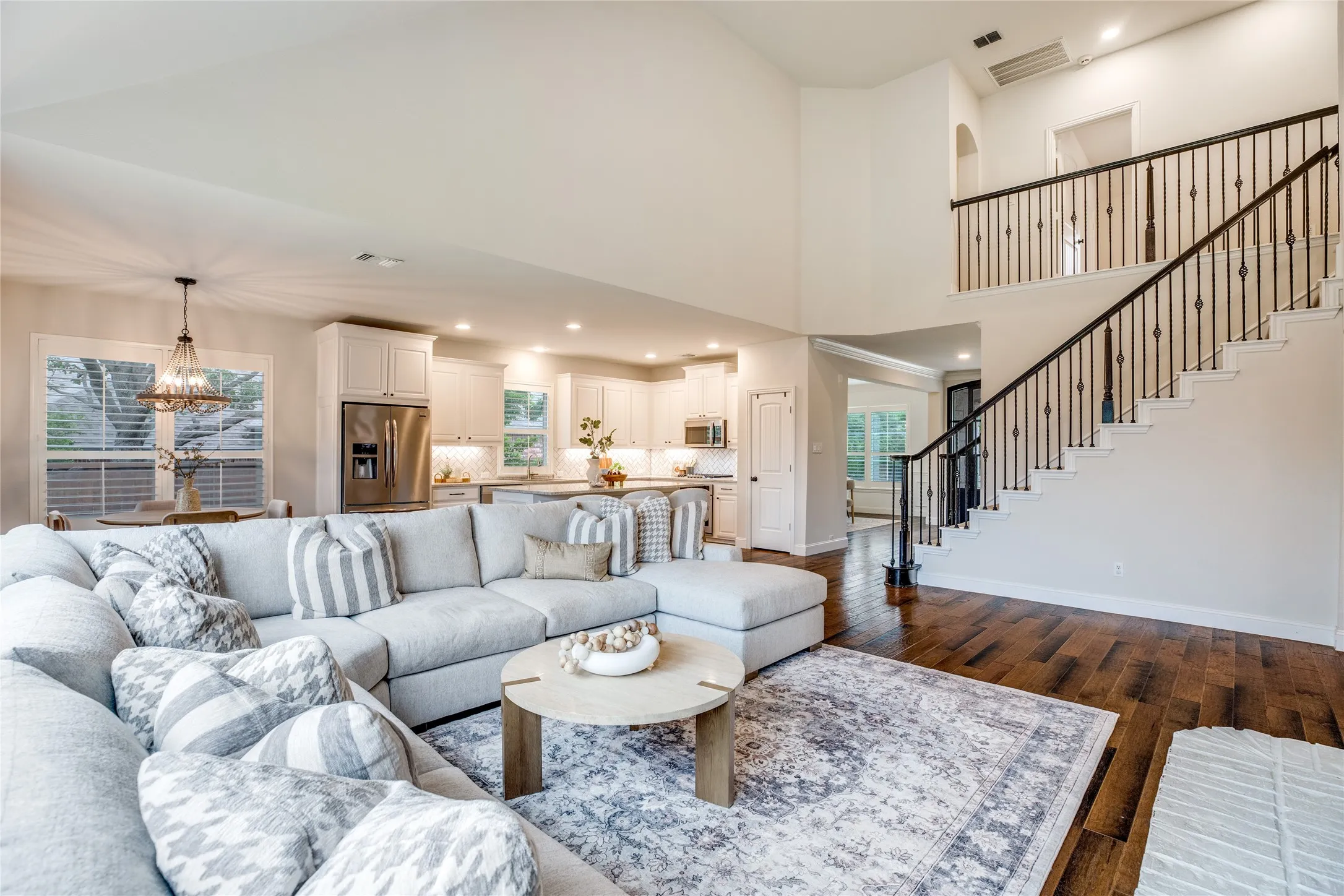 This open-concept living space features hardwood floors and a grand staircase with dark railings