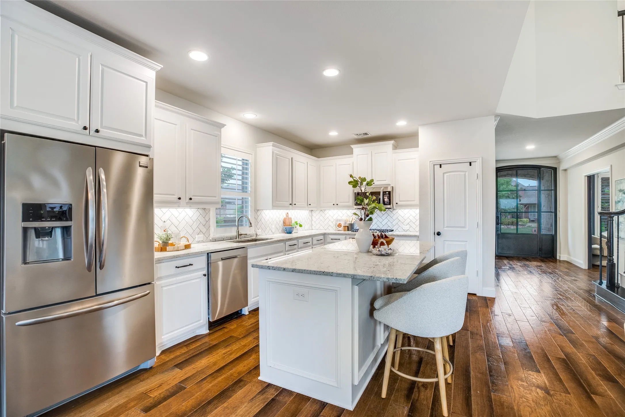The kitchen features white cabinetry, stainless steel appliances, and a light-colored countertop