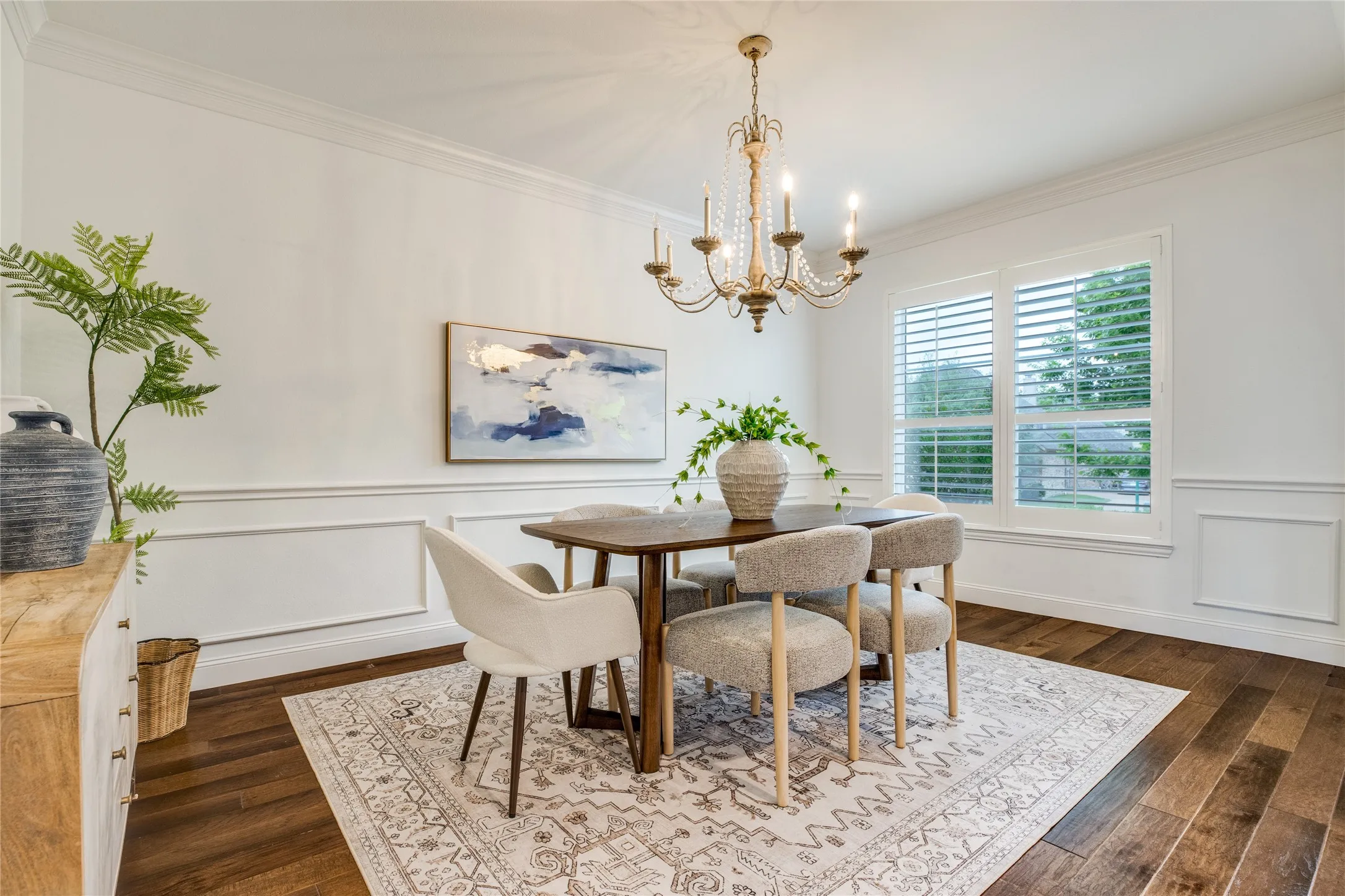 The dining area features hardwood floors, a decorative chandelier, and wainscoting on the walls