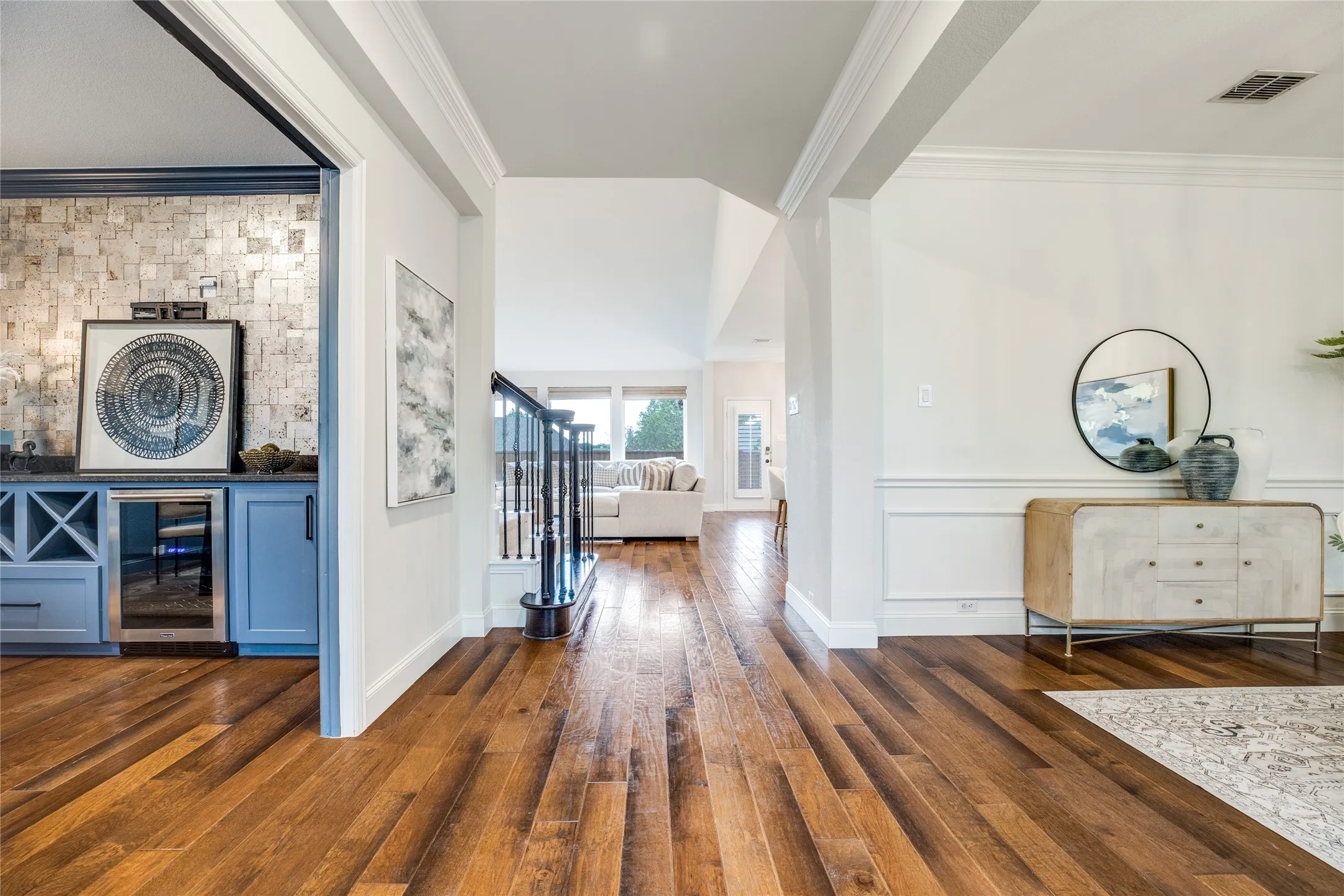 The property features polished hardwood floors, a built-in wet bar with a beverage cooler, and a stylish staircase with black iron balusters