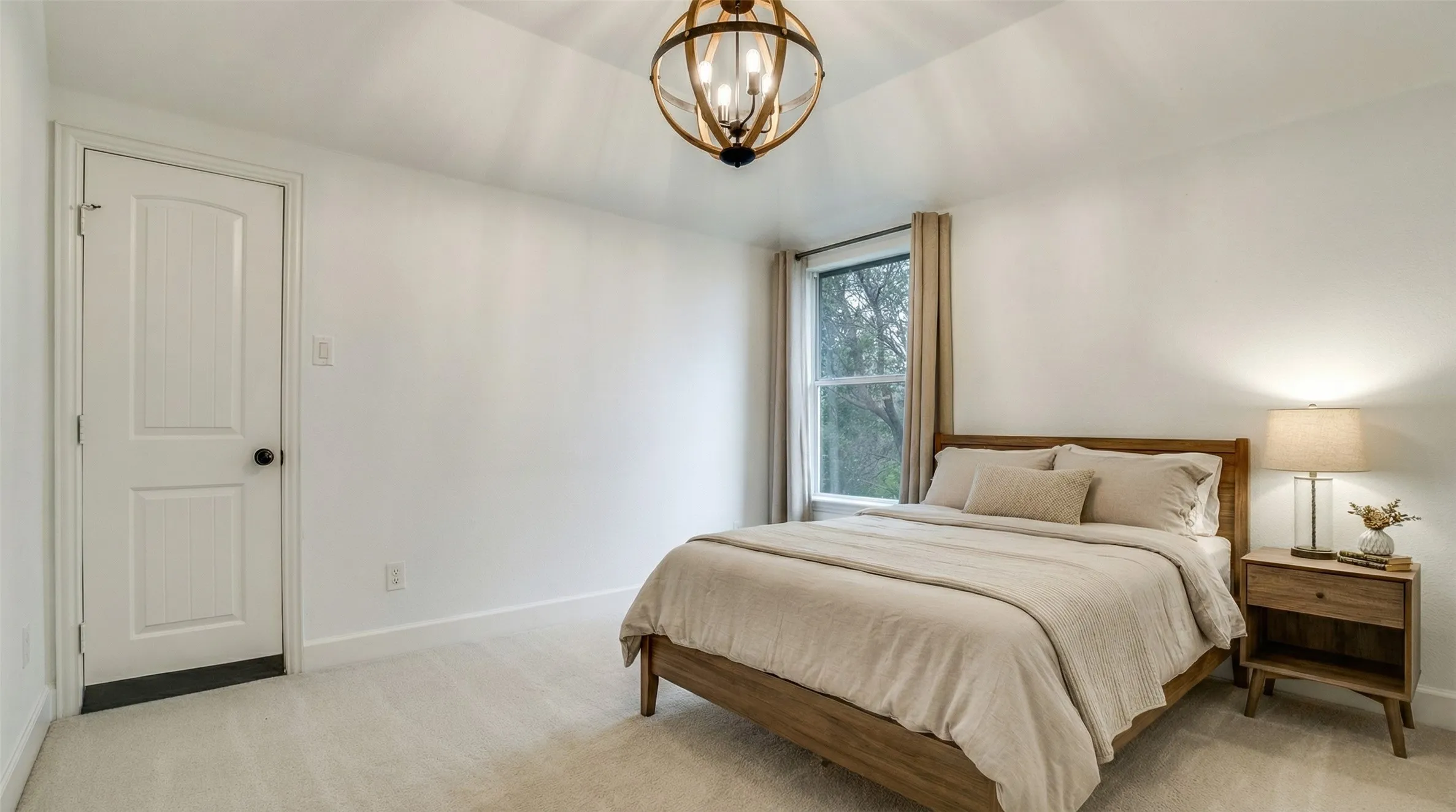 This inviting room features a neutral color palette, a window with exterior views, and a stylish chandelier