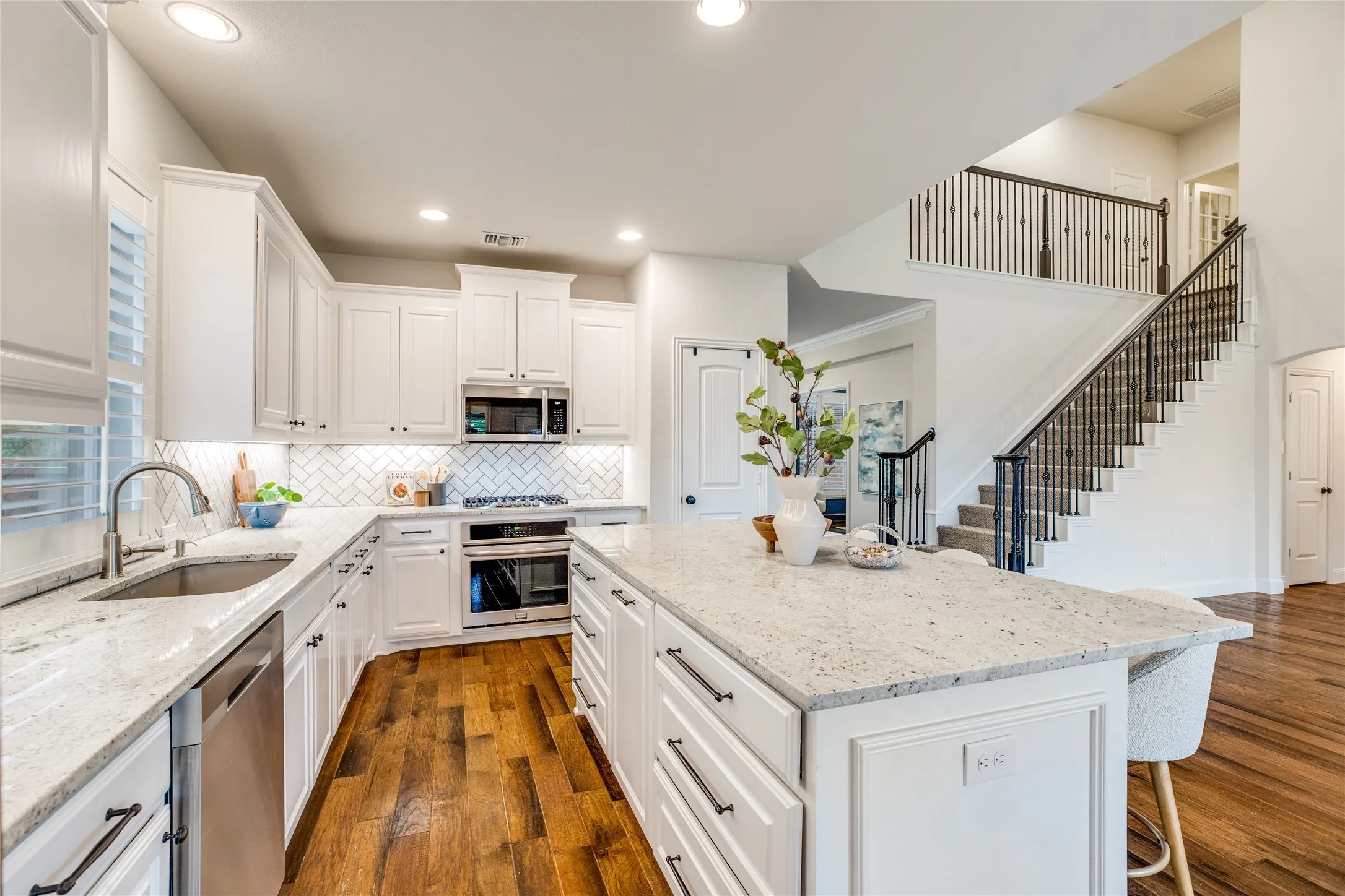 The kitchen features white cabinetry, granite countertops, and hardwood flooring