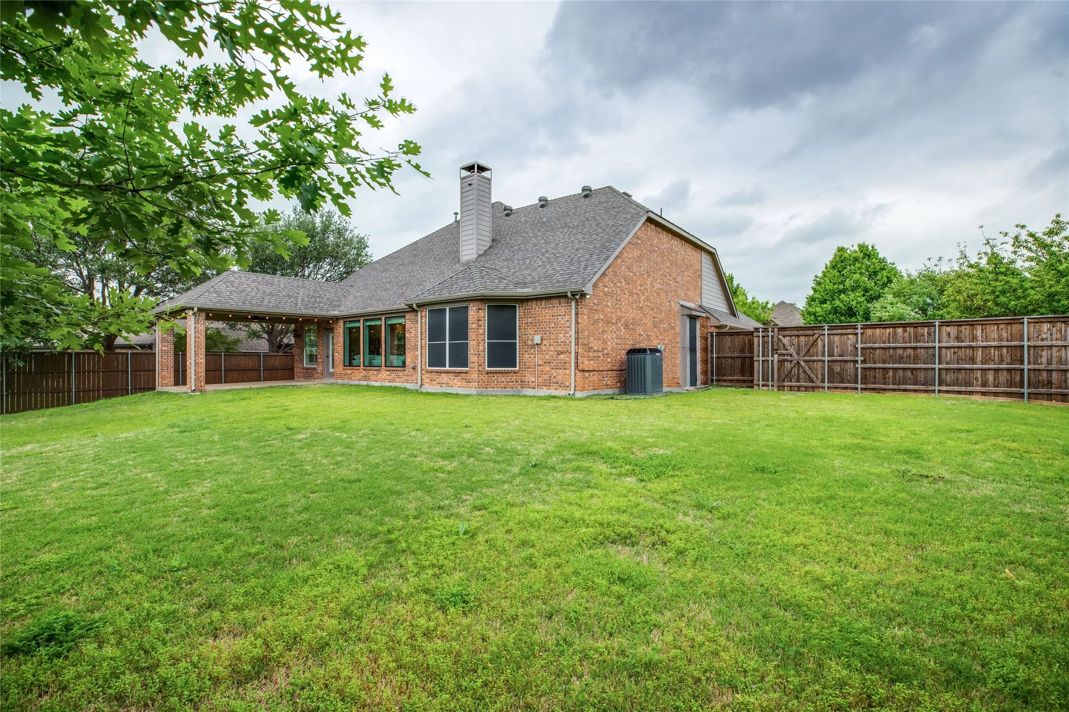 Expansive backyard featuring a well-maintained lawn, a covered patio, and privacy fencing