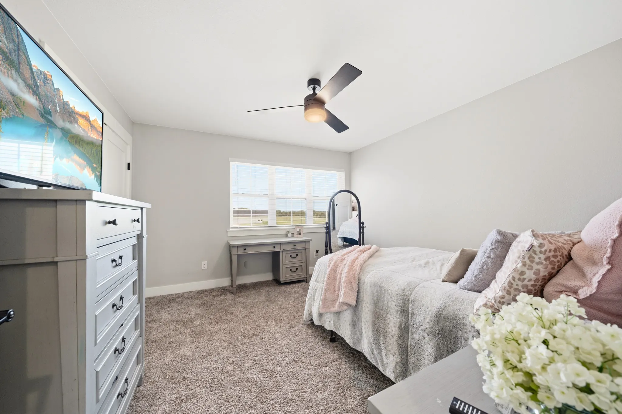 This room features neutral-toned carpeting, a window providing natural light, and a ceiling fan