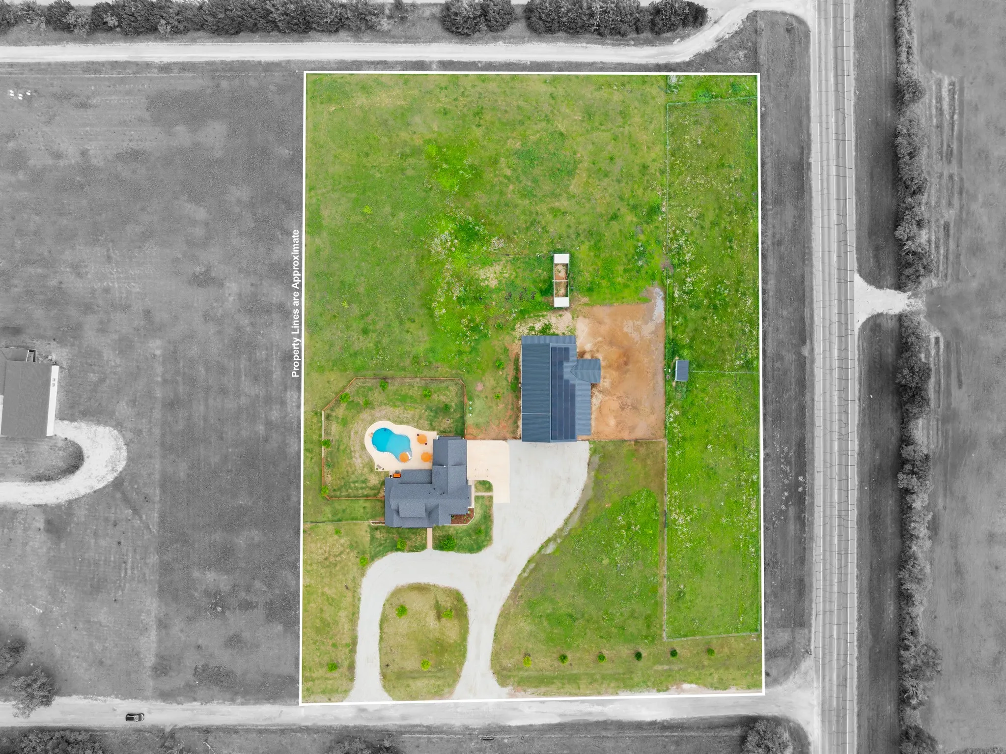 Aerial view showcasing the property's extensive grounds, featuring a private swimming pool, a spacious driveway, and multiple structures