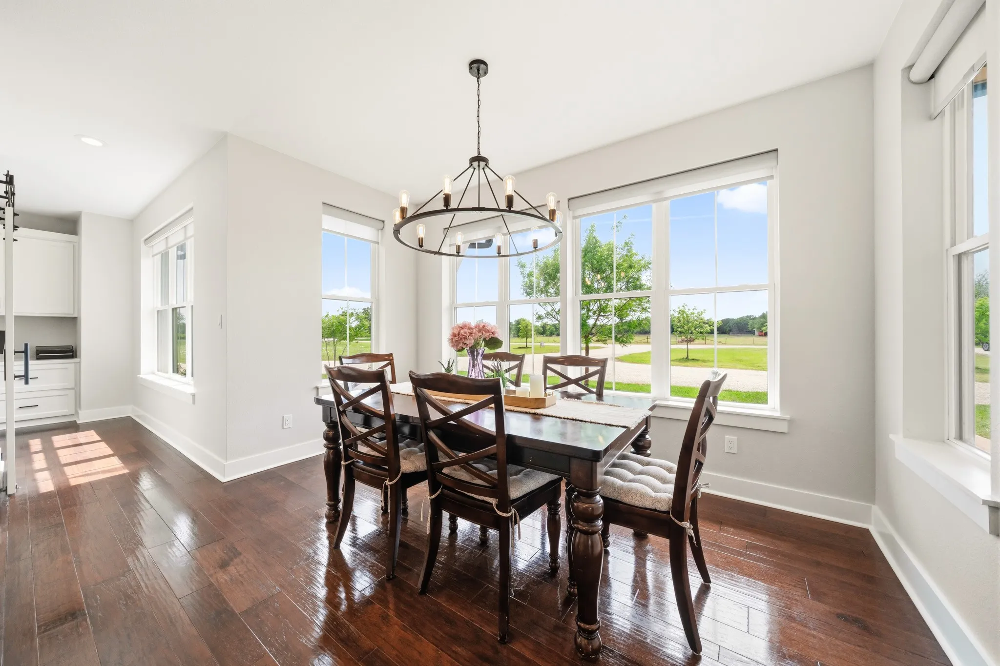 This dining area features rich hardwood flooring and large windows that provide ample natural light and views of the outdoors