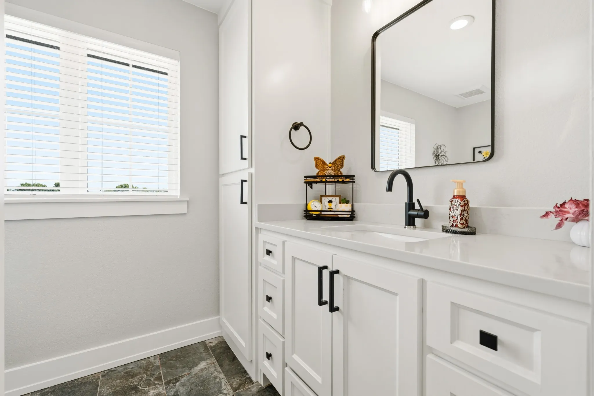 Bathroom featuring a single vanity with white cabinetry, a rectangular undermount sink, and a matte black faucet