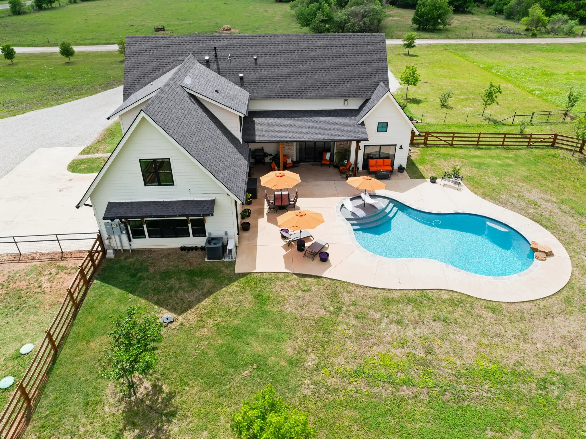 The property features a private swimming pool with a surrounding patio, a well-maintained lawn, and a fenced perimeter