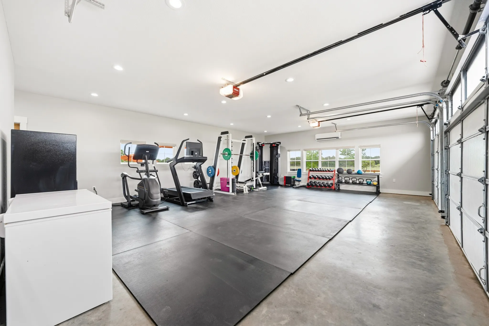 Spacious and versatile room featuring concrete flooring, recessed lighting, and windows providing natural light