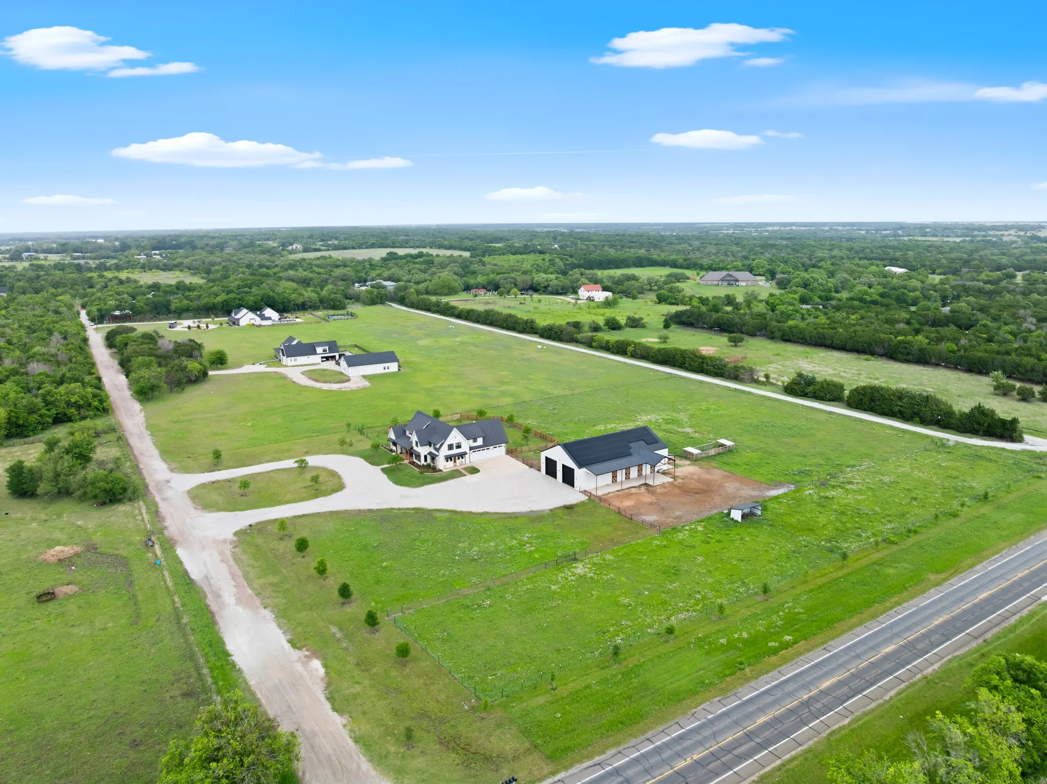 This aerial view showcases the property's expansive green grounds, featuring a main residence and a detached structure, all set within a lush, verdant landscape