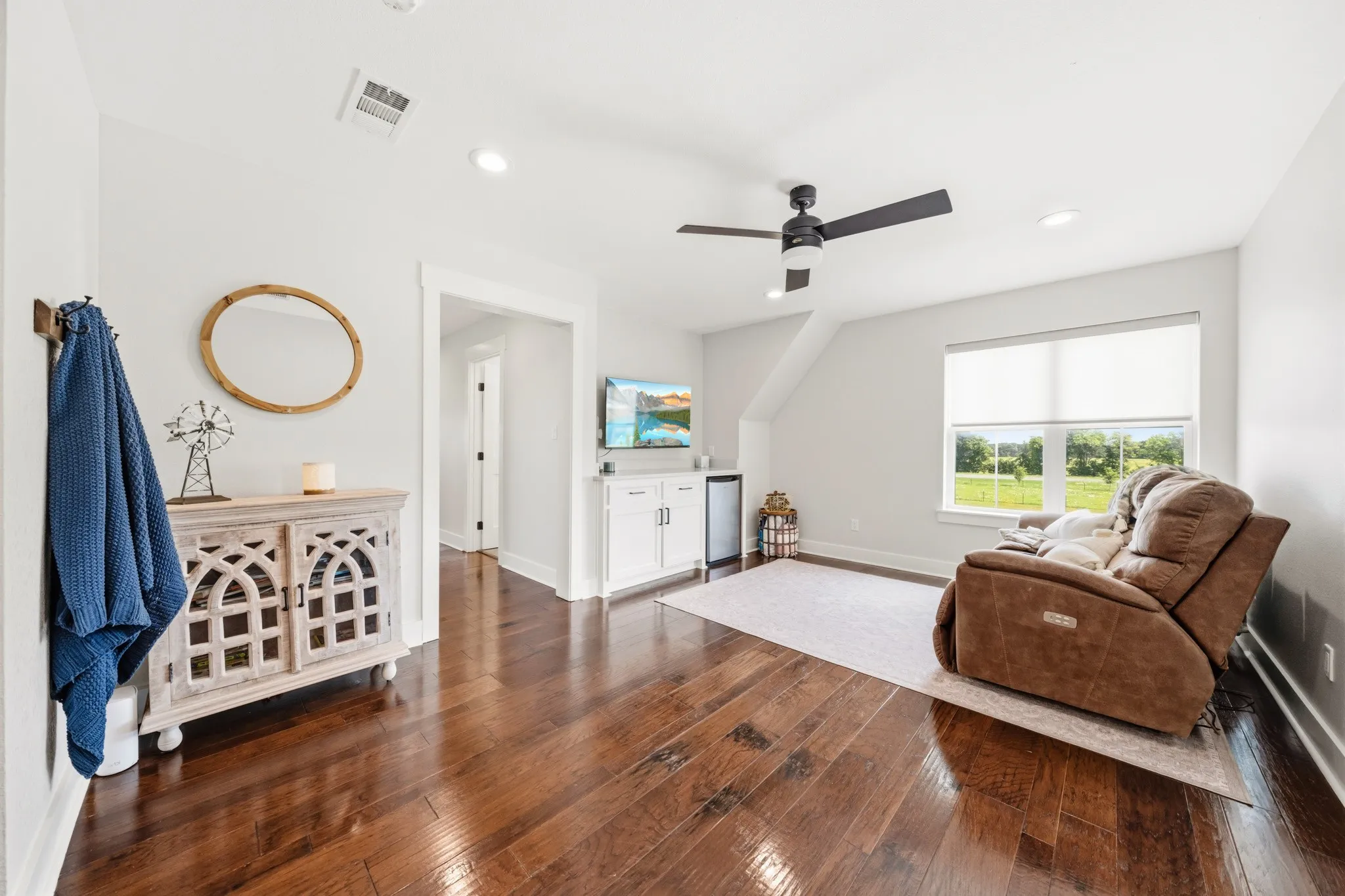 This inviting space features rich hardwood flooring, a ceiling fan, and recessed lighting