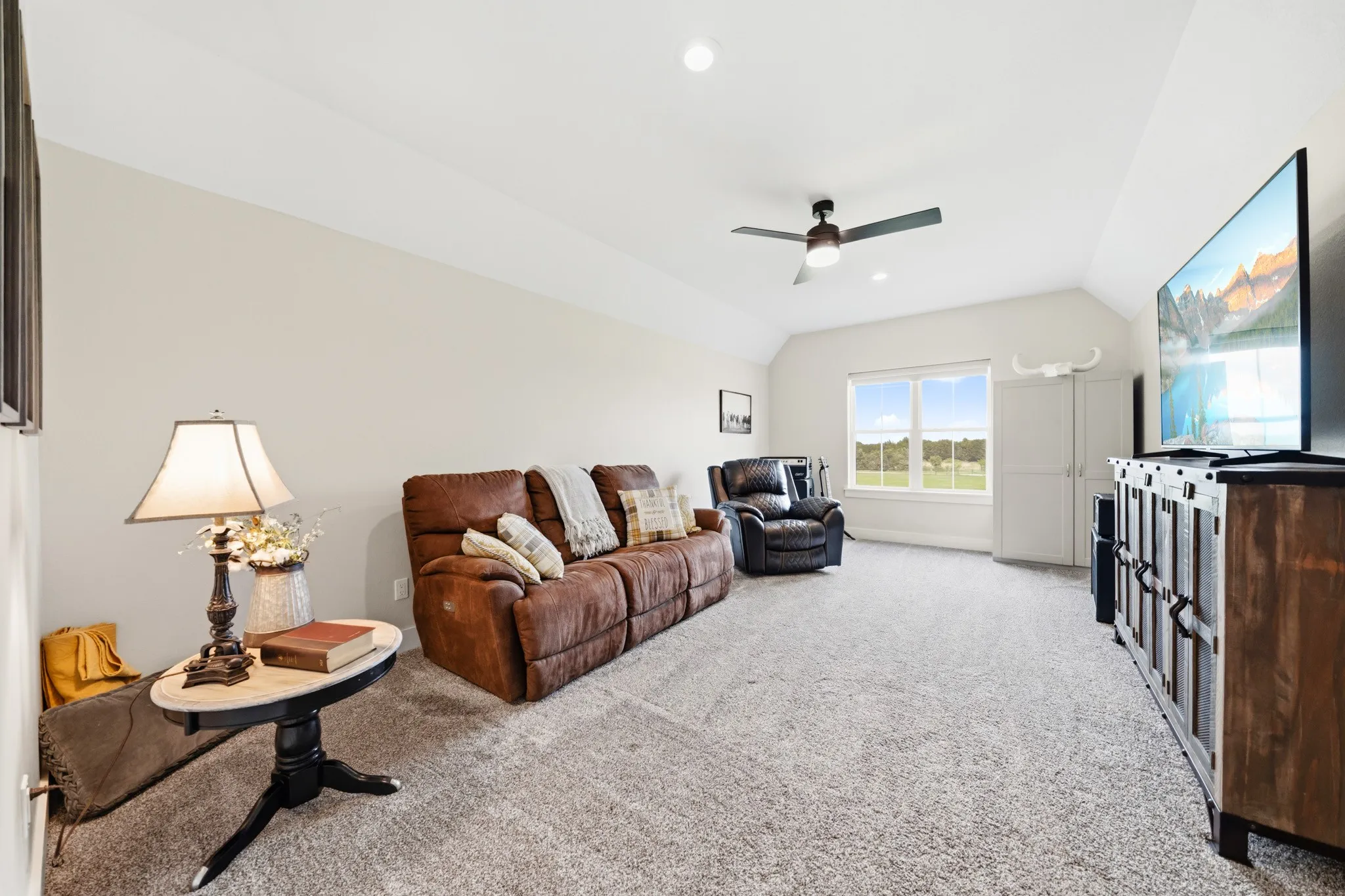 Spacious bonus room featuring vaulted ceilings, a ceiling fan, and carpeted flooring