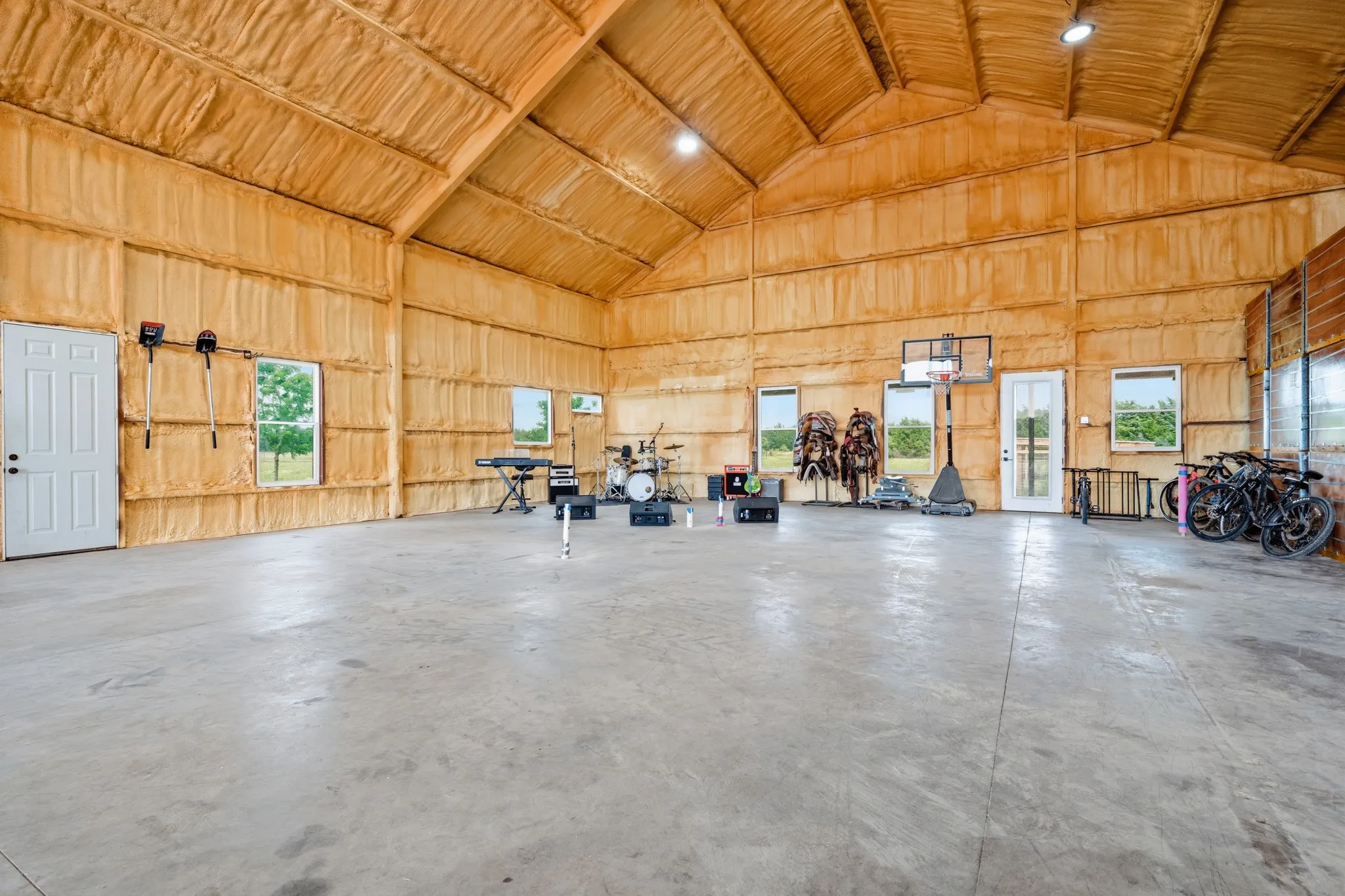 Spacious utility building with a high vaulted ceiling, concrete flooring, and well-placed windows allowing natural light