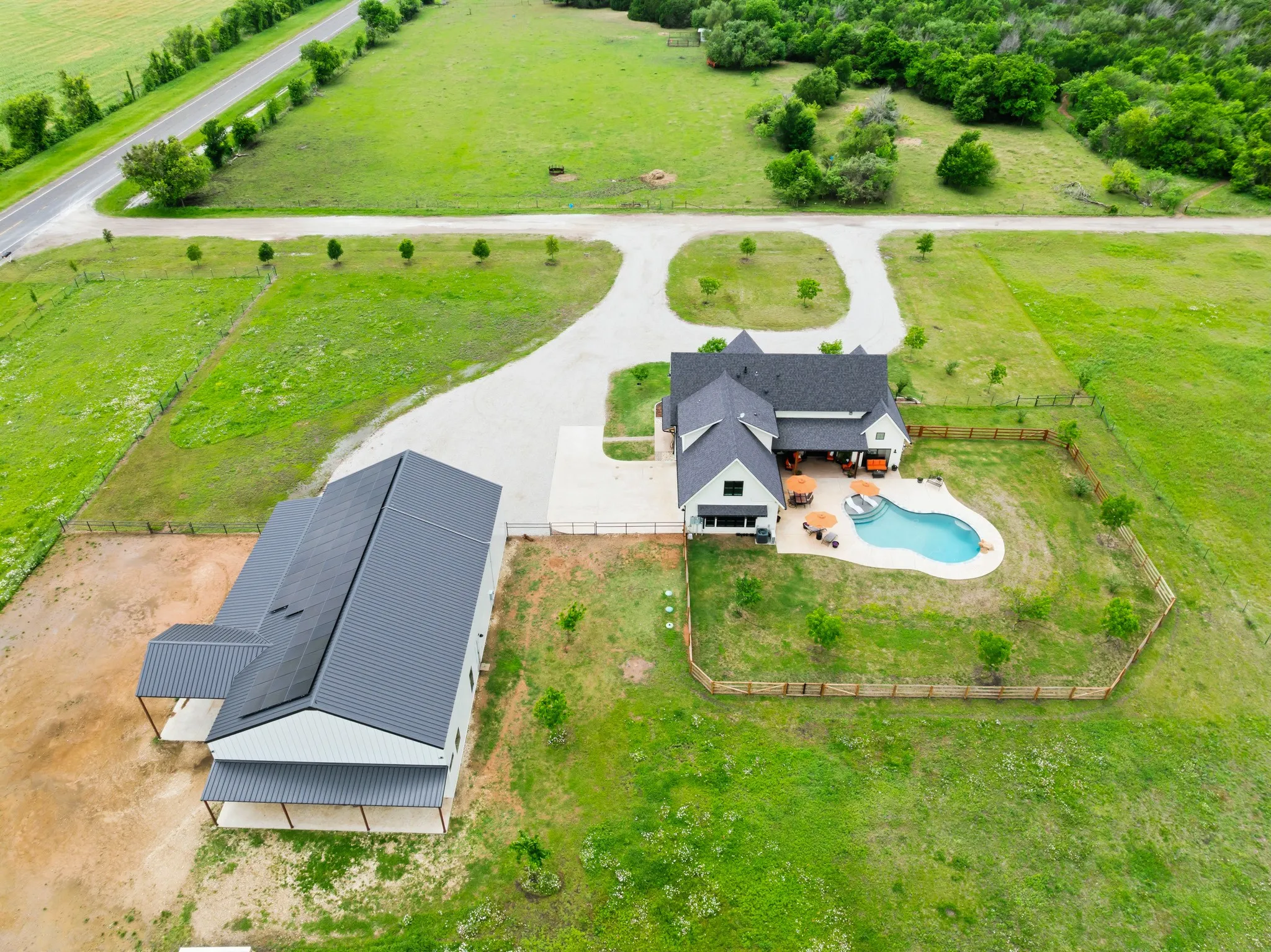 This property features a main residence with a swimming pool, a separate outbuilding, and expansive green grounds