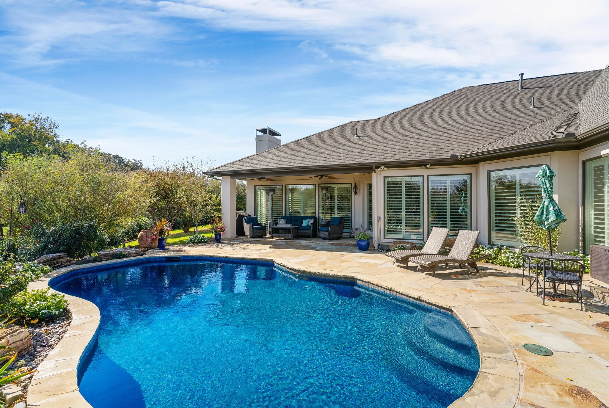 For those who love a backyard pool, this one is deep on the far end +...you'll appreciate the generous open & covered patio space for multiple lounging areas or dining under the open sky. Windows expand all along this side of the home to capture the allure of the glimmering swimming pool.