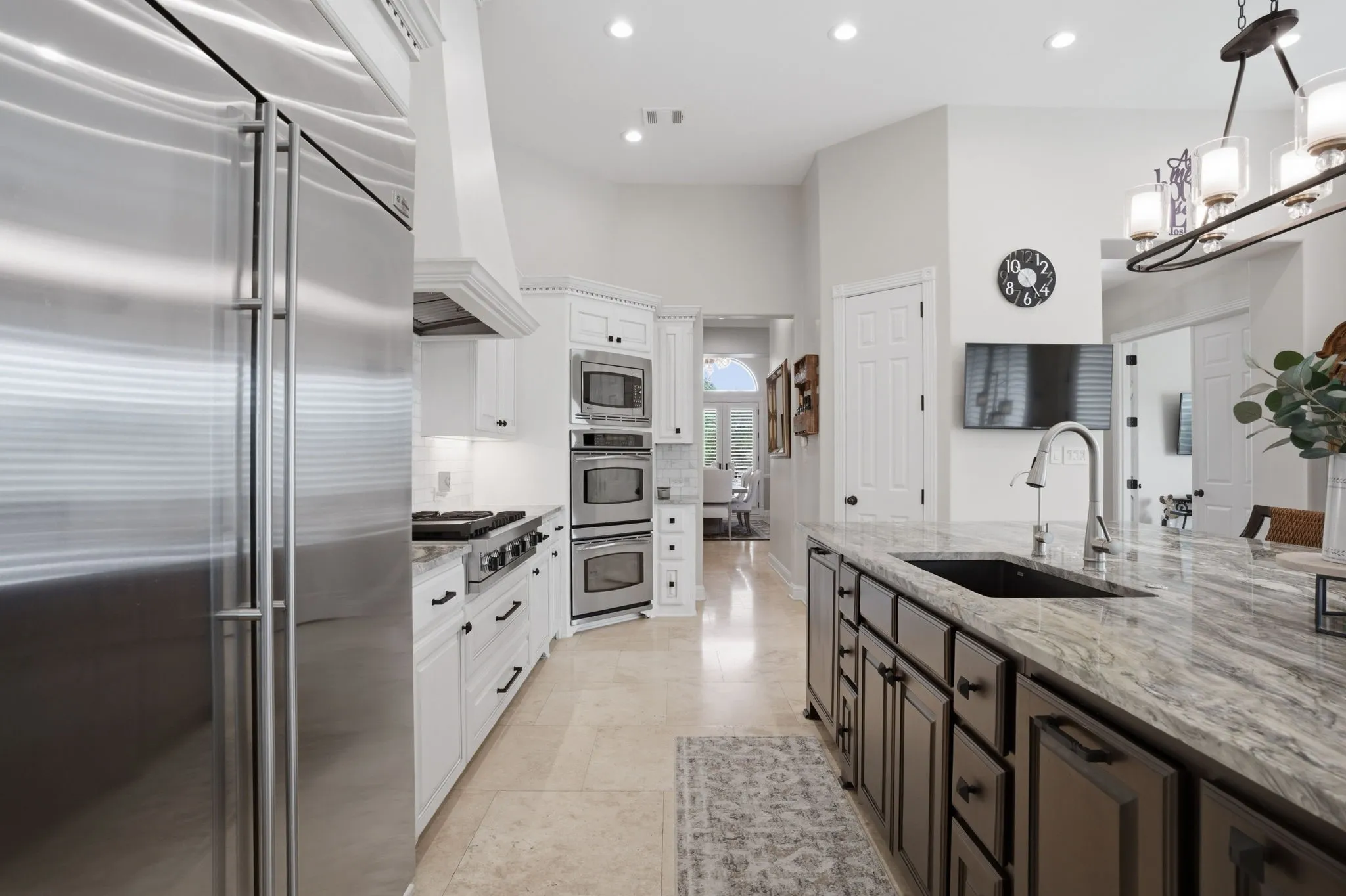 The kitchen remodel includes the addition of a trash drawer, vertical tray cupboard, the deep farm sink, reverse osmosis system installed + cabinet hardware. Walk-in pantry through the corner door straight ahead.