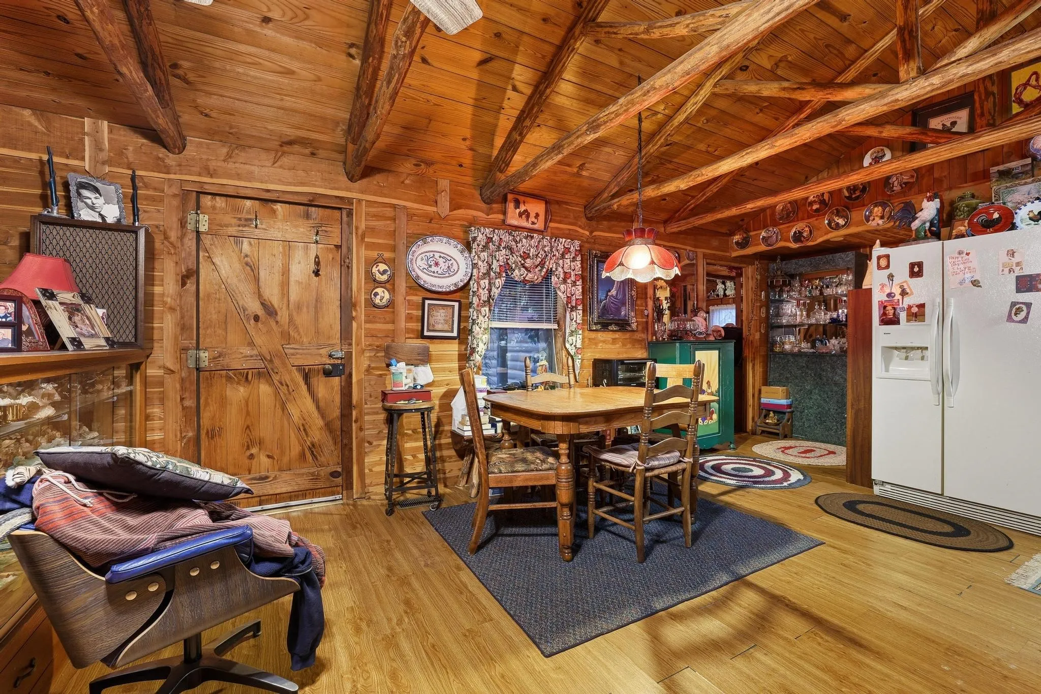 Dining area featuring wood paneled walls, exposed wood ceiling beams, and a wood plank floor