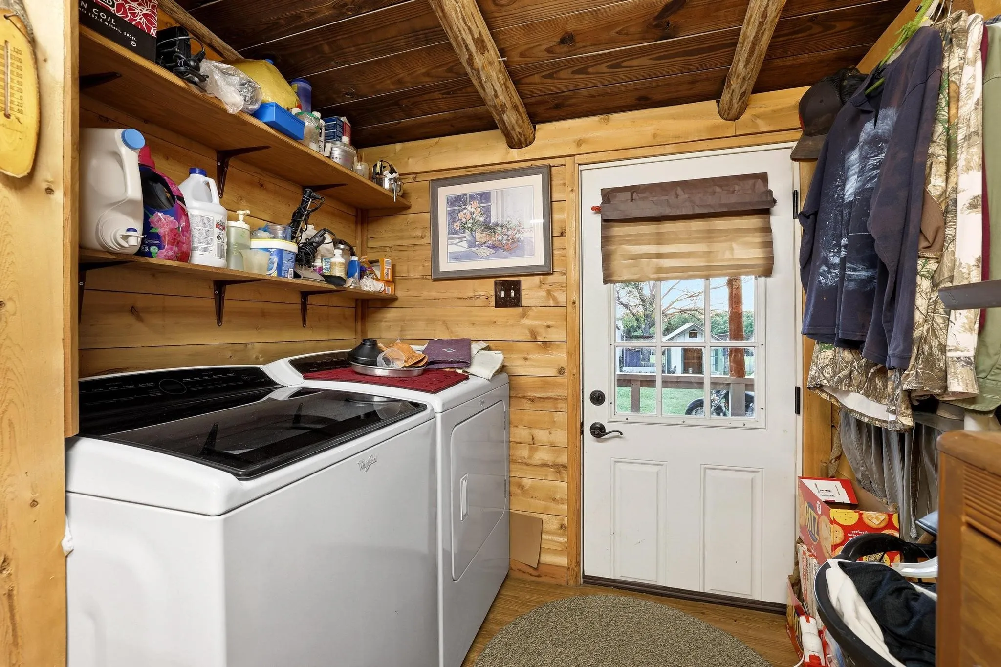 Laundry area featuring wood plank walls and ceiling, exposed wood beams, and built-in shelving