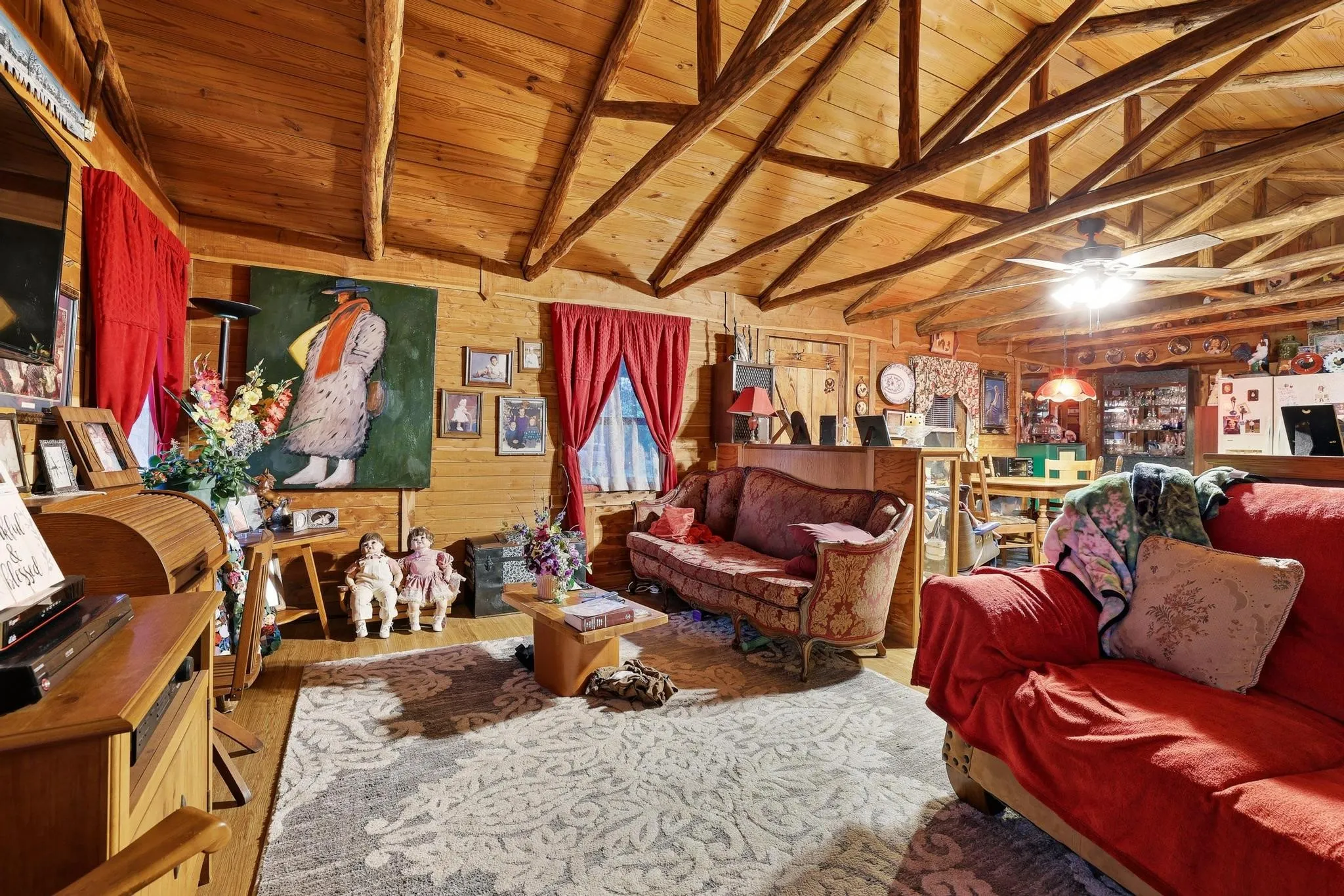 The living area features a high vaulted ceiling with exposed wooden beams, natural wood paneled walls, and a ceiling fan with integrated lighting