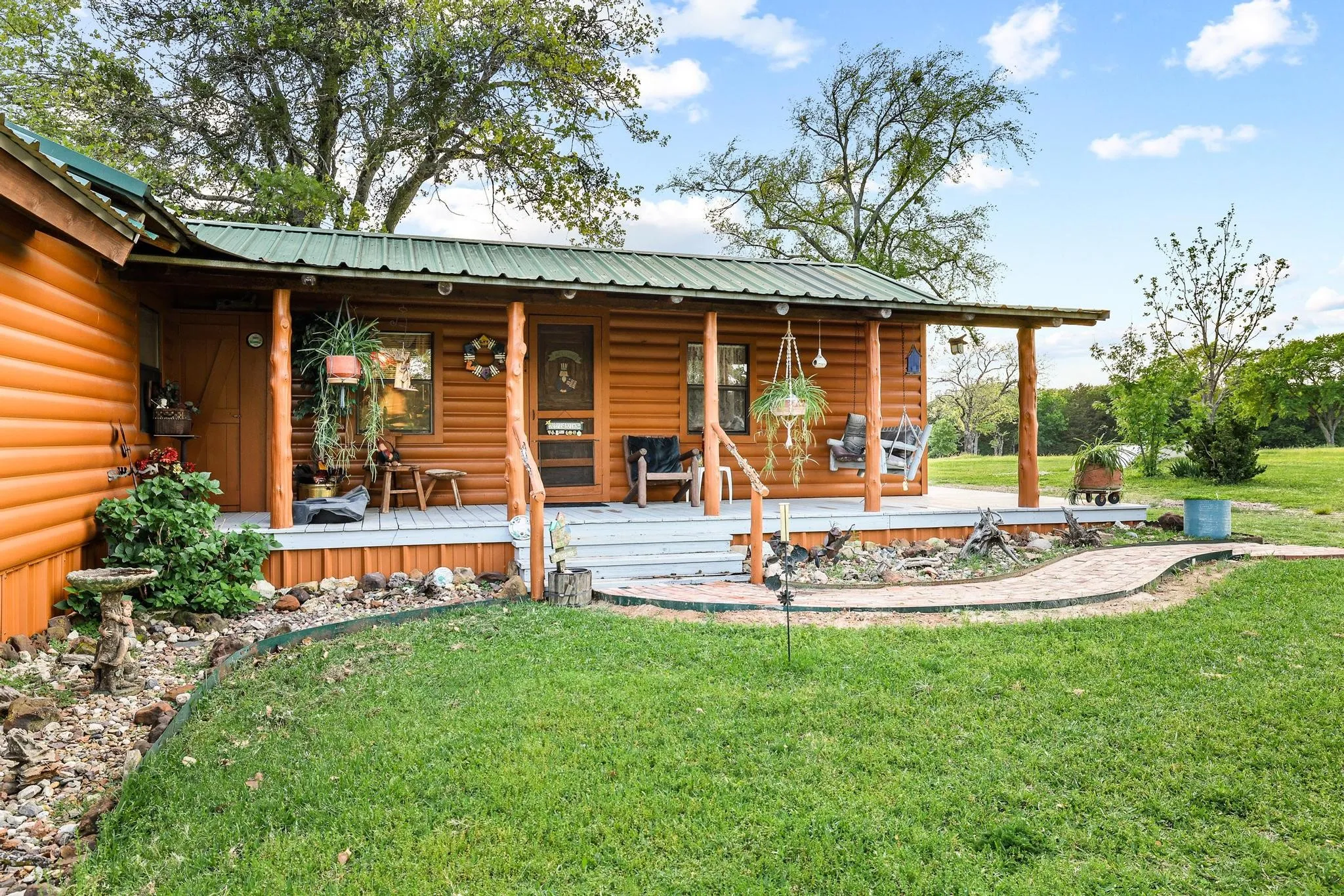 The property features a charming wooden exterior with a green metal roof and a spacious covered porch
