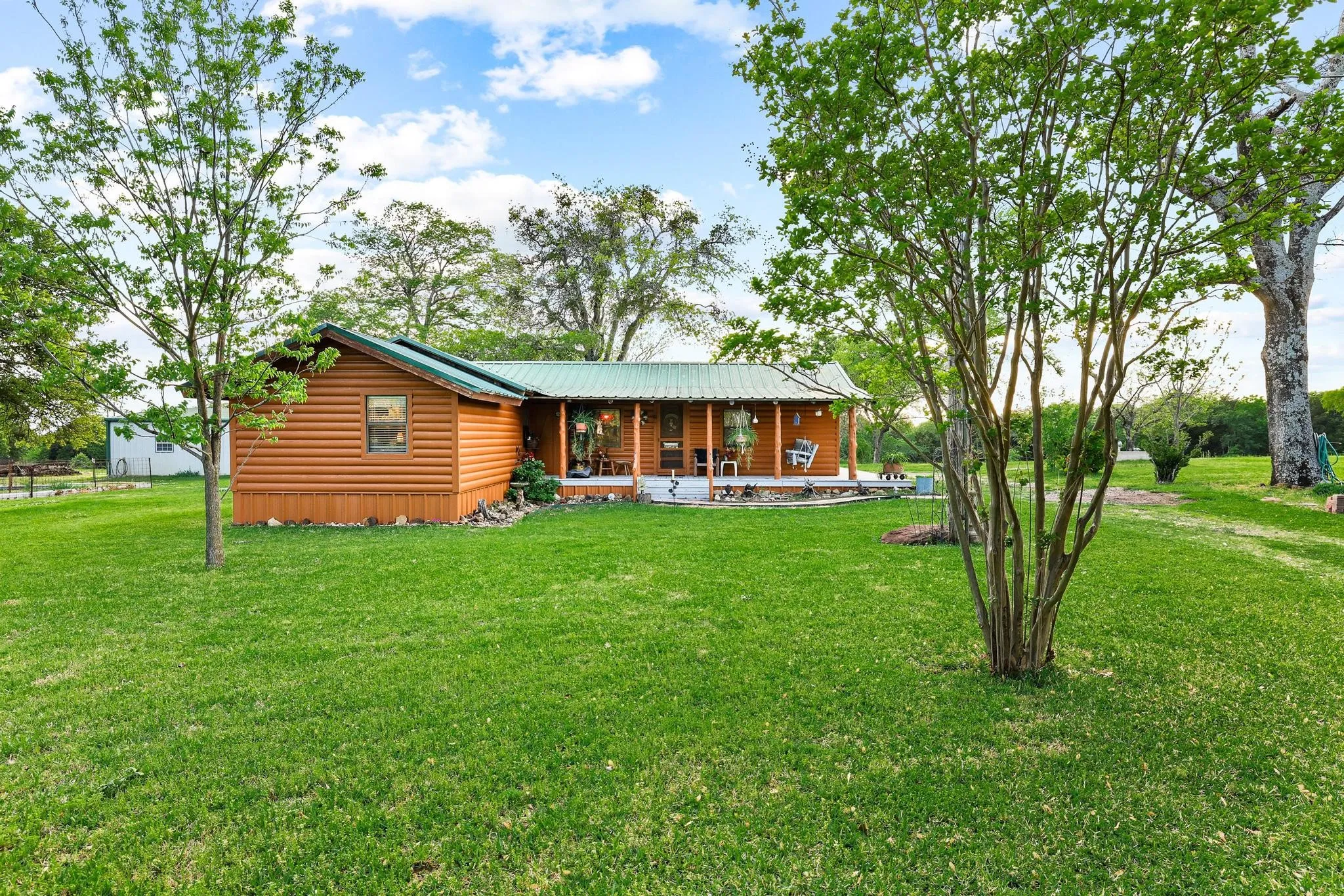 The property features a log cabin style exterior with a green metal roof and an inviting covered porch