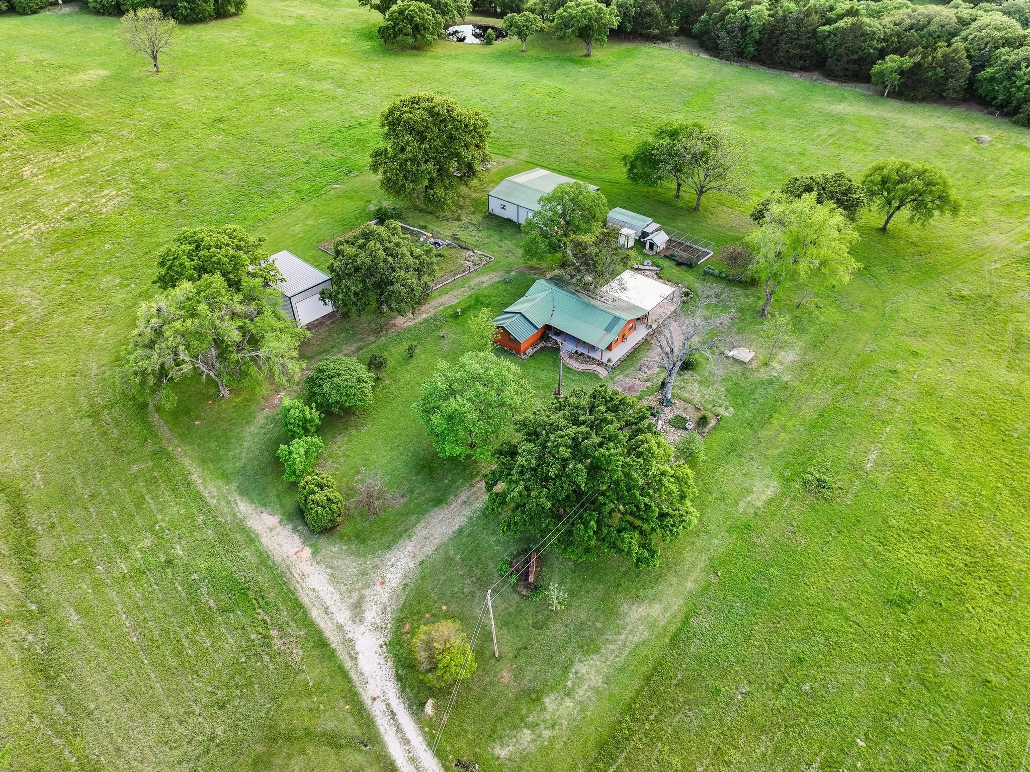 The property features an extensive green landscape with mature trees and multiple outbuildings