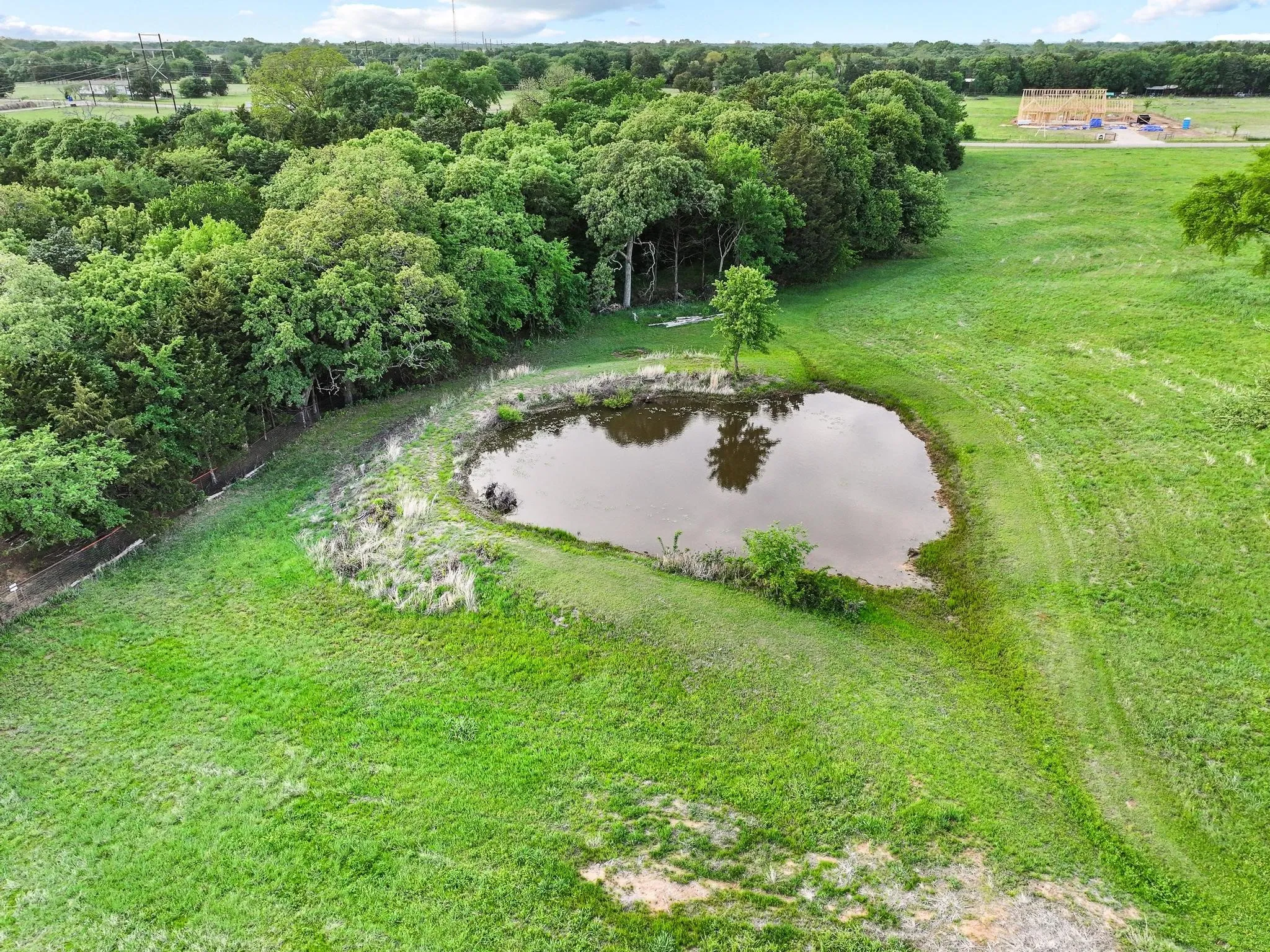The property features a pond surrounded by extensive green grass and mature trees