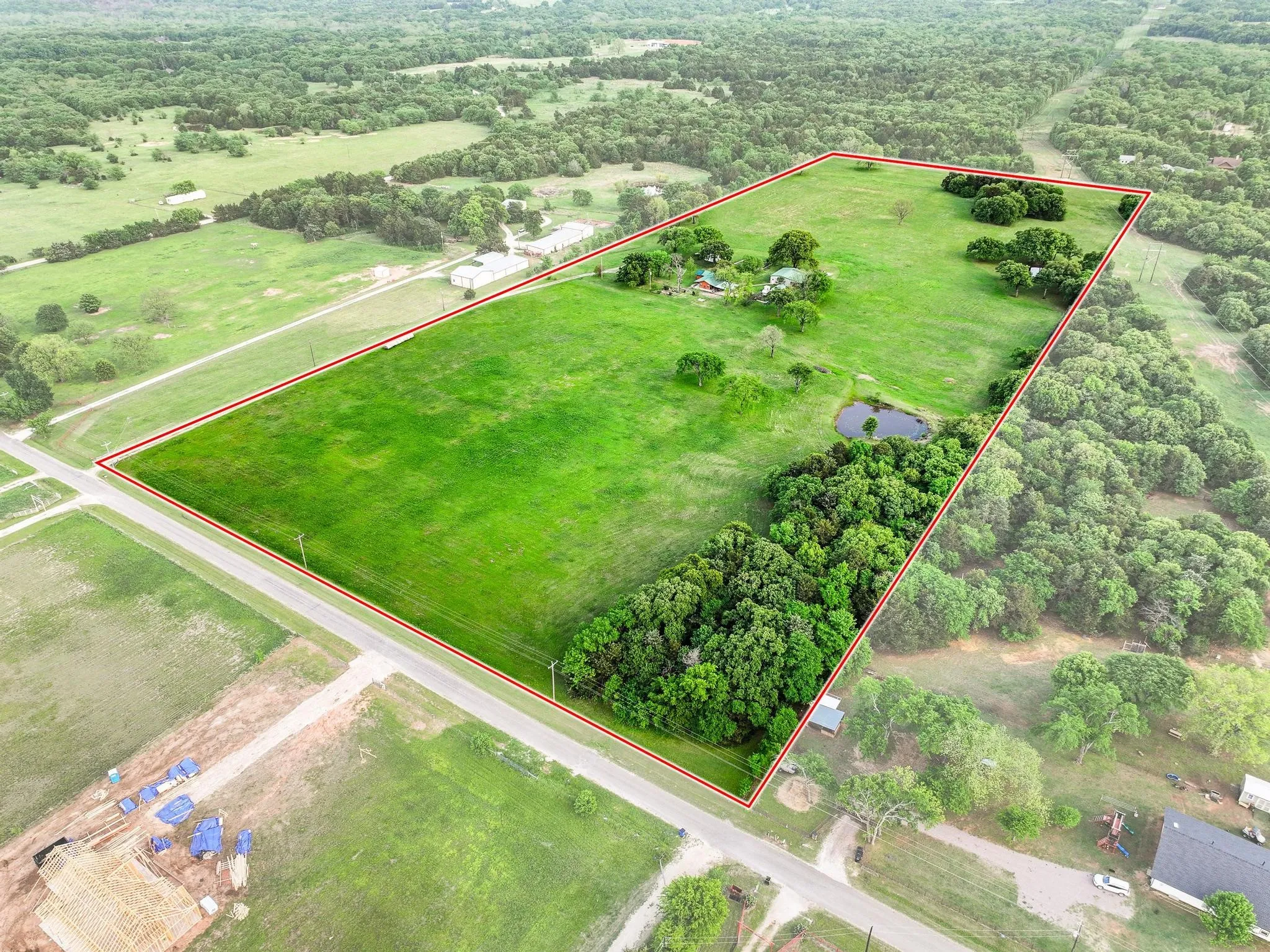The property features a pond surrounded by extensive green grass and mature trees