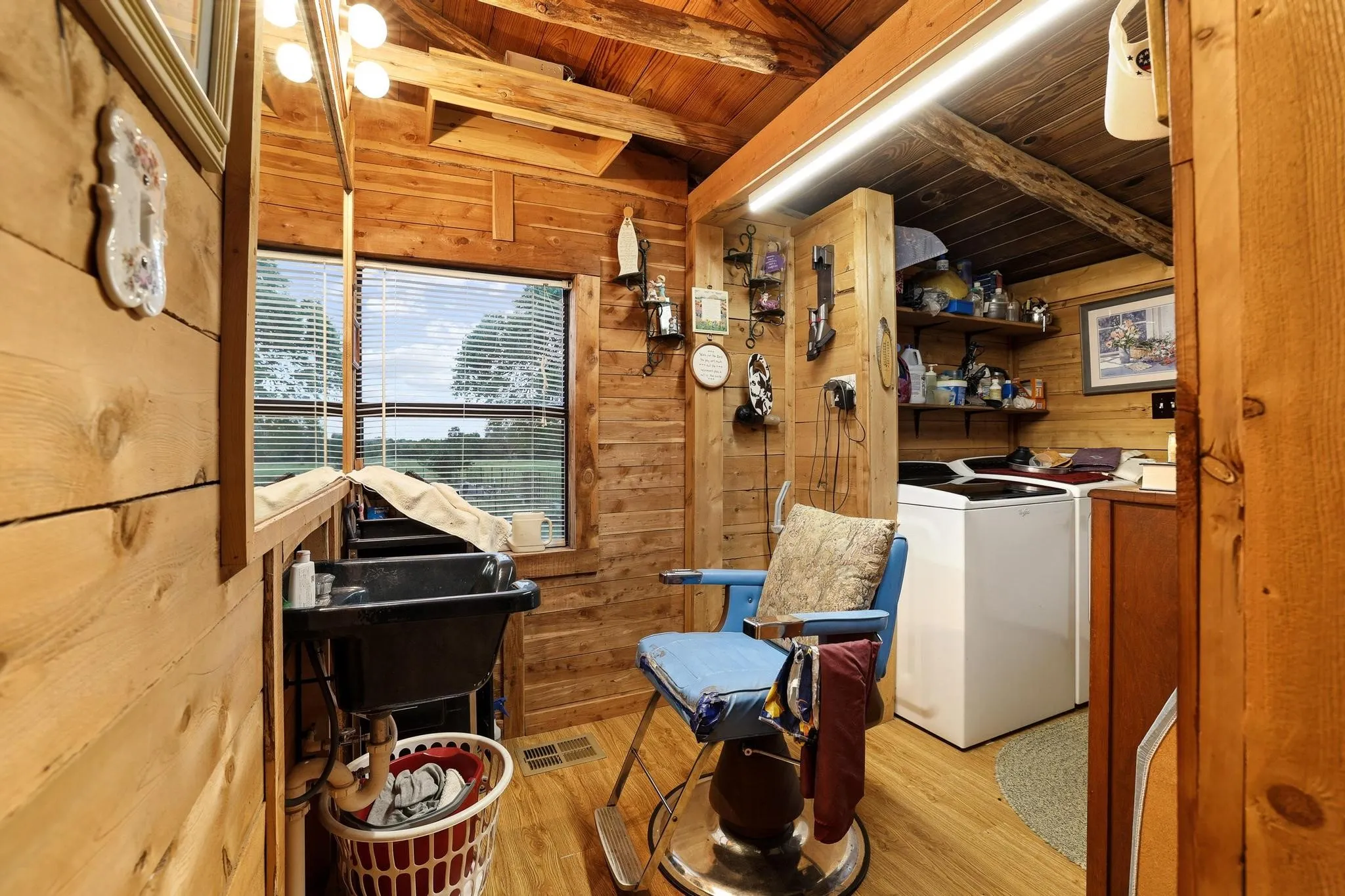 Interior room with natural wood paneling, wood flooring, and a large window with horizontal blinds