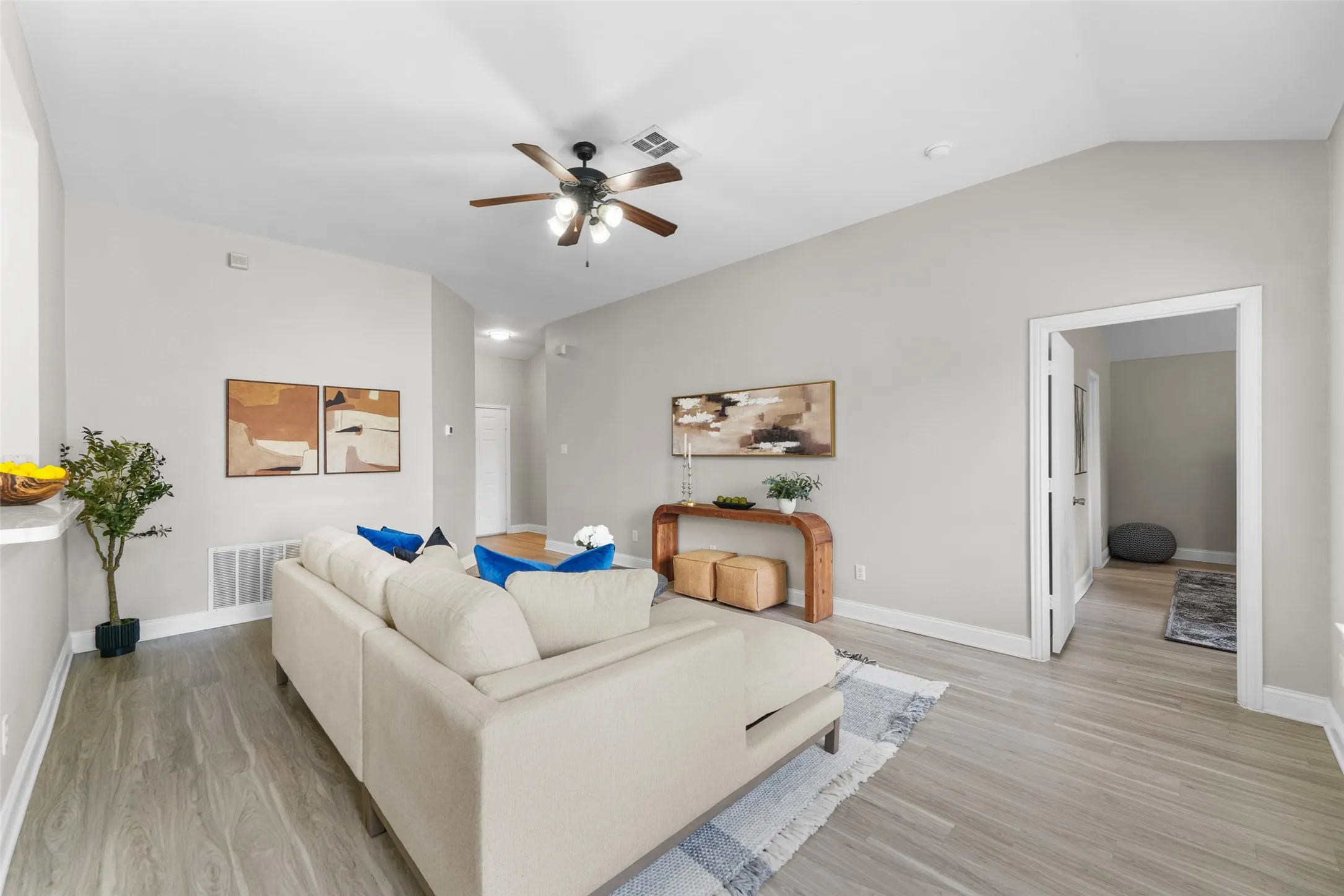 Virtually staged. Living room featuring ceiling fan, light wood-style floors, and vaulted ceiling
